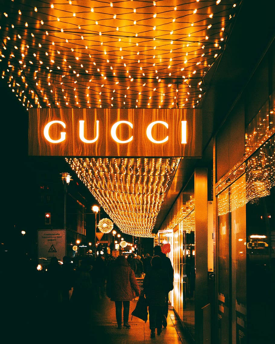 金色燈光在夜晚照亮了Gucci商店附近的繁華城市街道。 — Gucci GIF 壁紙
