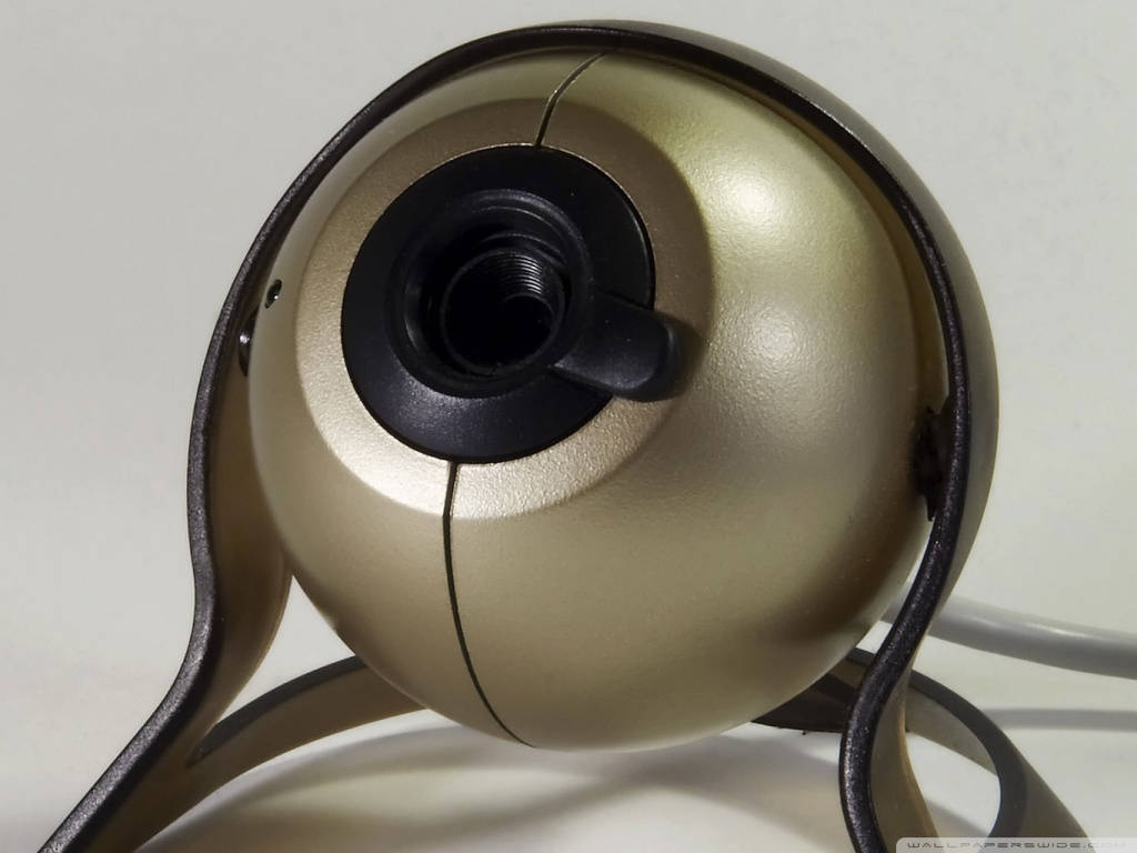 Webcam 桌布 壁紙 — 金色球形網路攝影機的特寫，帶有黑色裝飾和可見鏡頭，背景為純白色。
