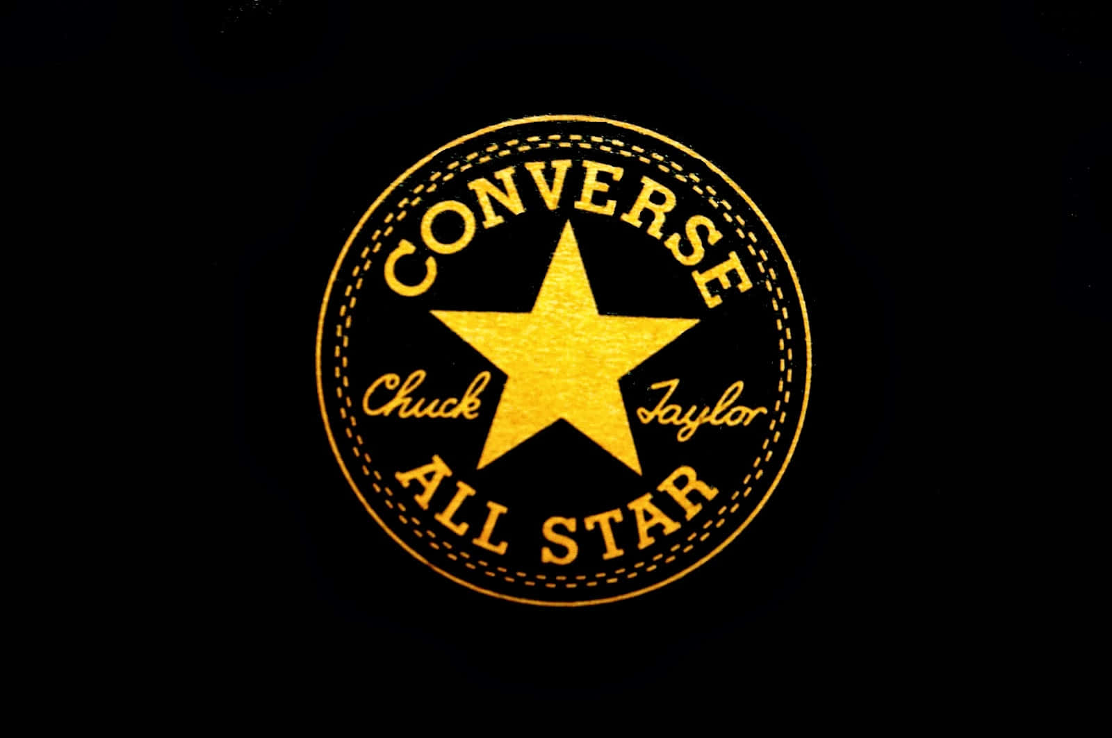 Converse Logo 桌布 壁紙 — 金色的Converse All Star標誌，帶有星星和縫合圓圈，在黑色背景上發光。