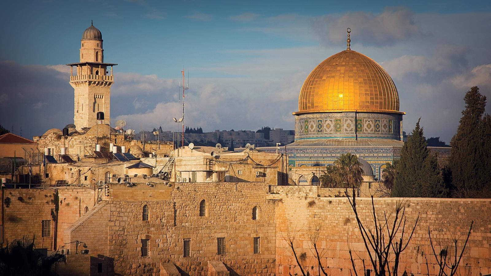 Jordan 桌布 壁紙 — 金色的圓頂清真寺在藍天下溫暖地發光，陽光沐浴著耶路撒冷古老的石頭建築和光禿的樹木。