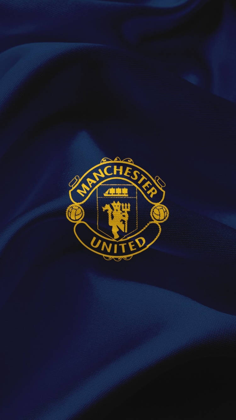 Manchester United Logo 桌布 壁紙 — 金色的曼聯會徽在華麗的皇家藍色緞面上閃耀，帶有戲劇性的褶皺和柔和的光線。