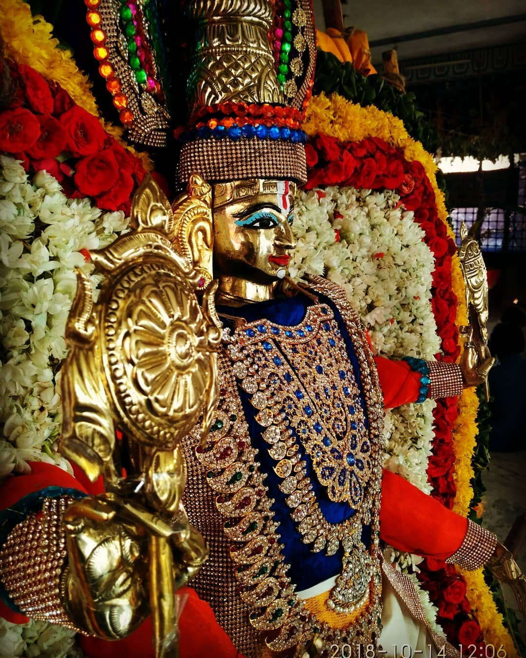 Hindu Temple 桌布 壁紙 — 金色神像，飾以精緻珠寶和由紅、白、黃色花朵組成的鮮豔花環。