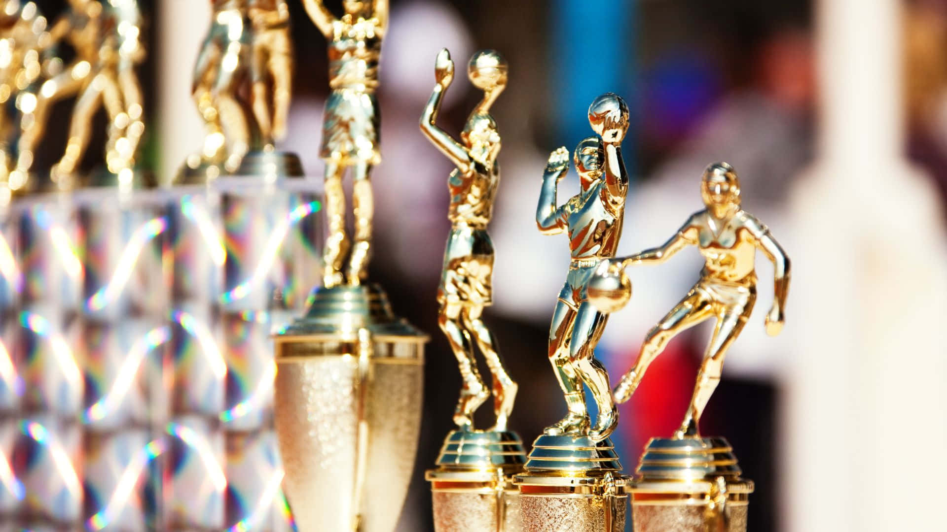 Best Sports 桌布 壁紙 — 金色籃球獎盃在模糊多彩的背景上，以反光表面和水晶底座閃耀光芒。