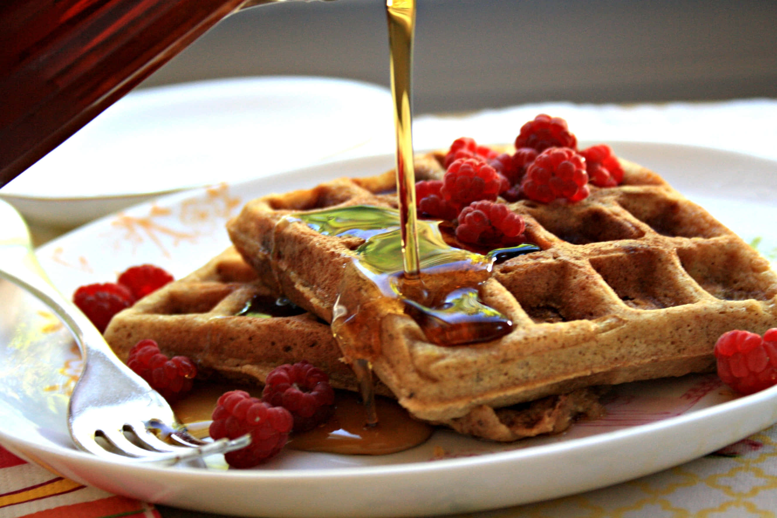 Waffle 桌布 壁紙 — 金色糖漿從白色盤子上的新鮮覆盆子鬆餅上流下。