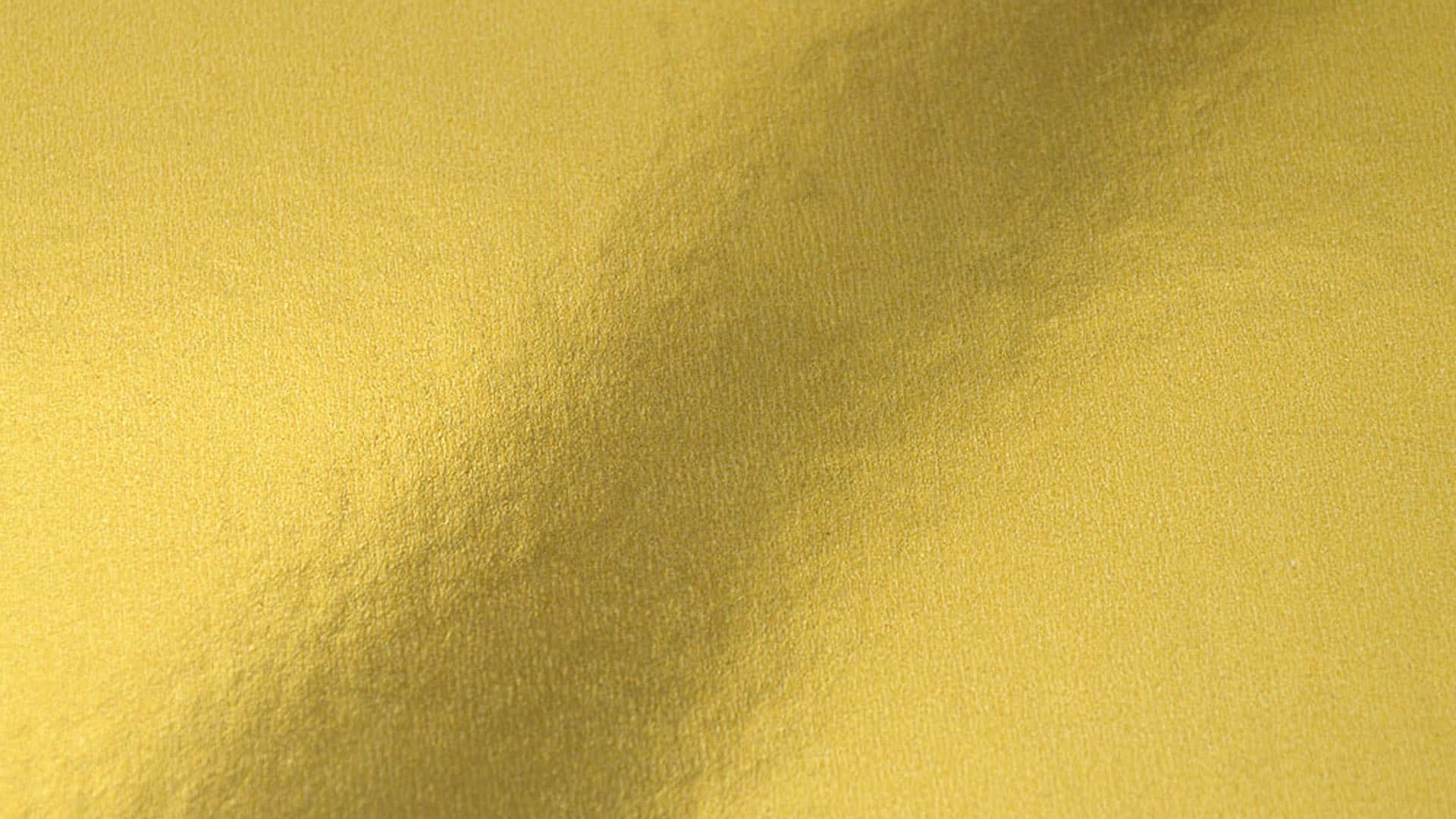 Metallic Gold 桌布 壁紙 — 金色紋理布料的特寫，帶有柔軟的皺褶和微妙的燈光變化，營造出奢華閃爍的效果。