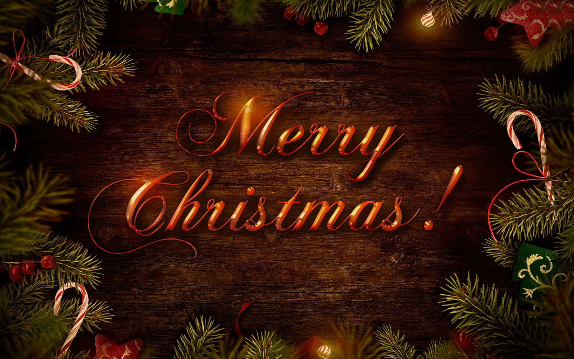 聖誕節 桌布 壁紙 — 金色草書 Merry Christmas 文字在由松樹枝、拐杖糖和節日裝飾品框住的質樸木質背景上溫暖地發光。