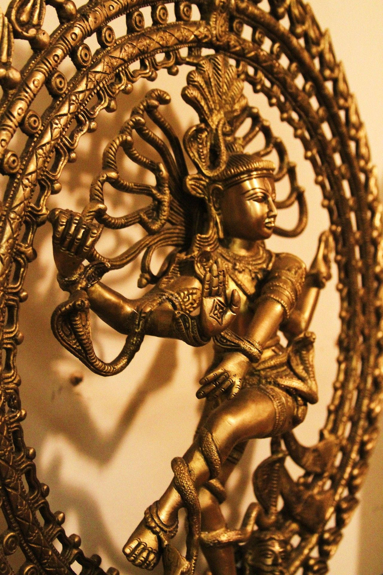 Indian 桌布 壁紙 — 金色華麗的多臂神像在複雜的圓形框架內跳舞，投射出溫暖的陰影。