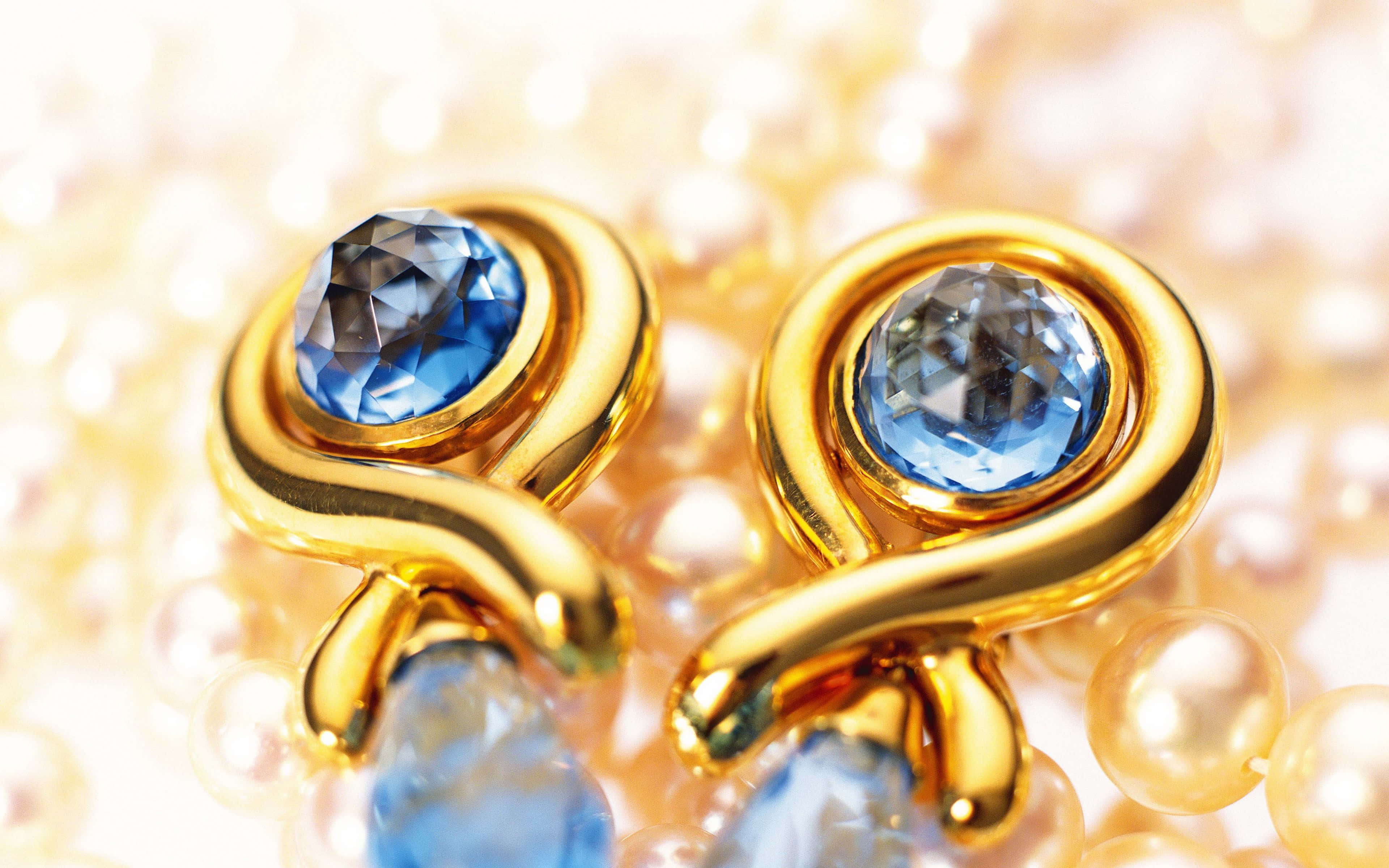 Earrings 桌布 壁紙 — 金色螺旋耳環鑲有藍色寶石，放在奶油色珍珠床上，在柔和溫暖的光線下。