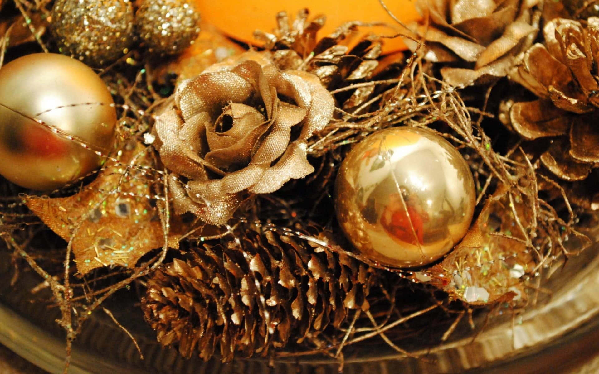 Gold Christmas 桌布 壁紙 — 金色裝飾品、松果和布料玫瑰緊貼在樹枝中的特寫，用於節日假期裝飾。