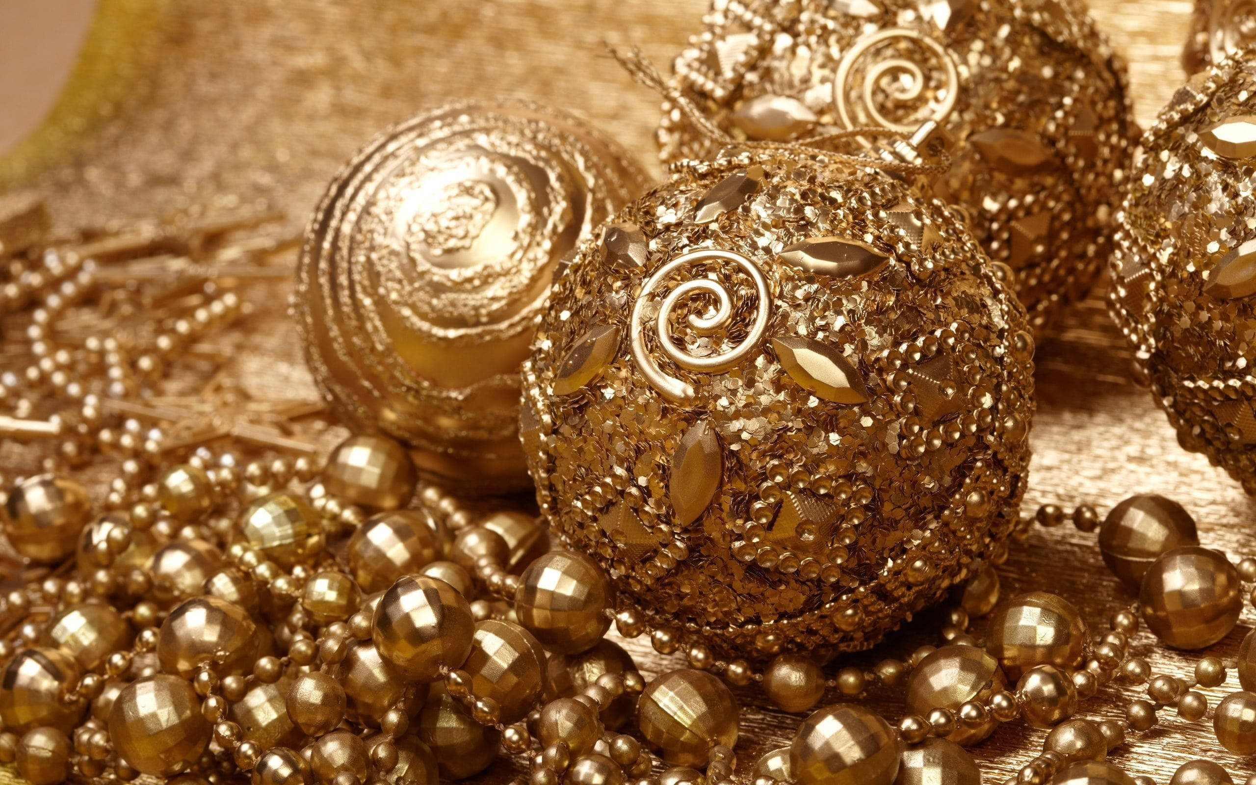 balls 桌布 壁紙 — 金色裝飾品和珠子在紋理金表面上閃爍著複雜的漩渦和閃閃發光的刻面。