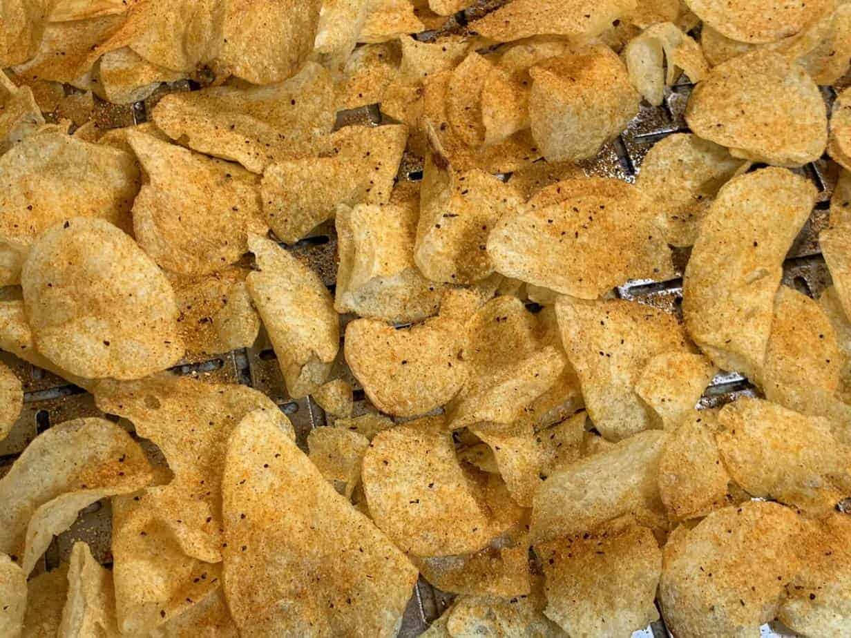 Snacks 桌布 壁紙 — 金色調味薯片堆疊在金屬架上的特寫，可見鹽和胡椒粒。