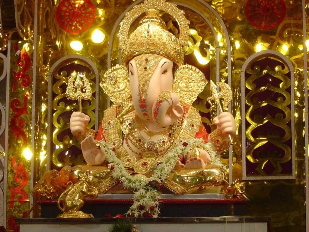 ganpati HD 桌布 壁紙 — 金色象神像飾以紅花和精緻珠寶，莊嚴地坐在閃閃發光的神龕中。