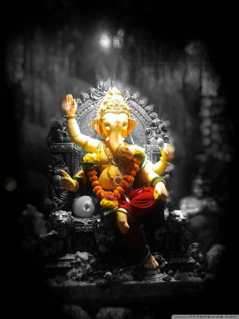 Ganesh 桌布 壁紙 — 金色象神雕像莊嚴地坐在華麗的寶座上，背後有發光的光環，背景為深色。