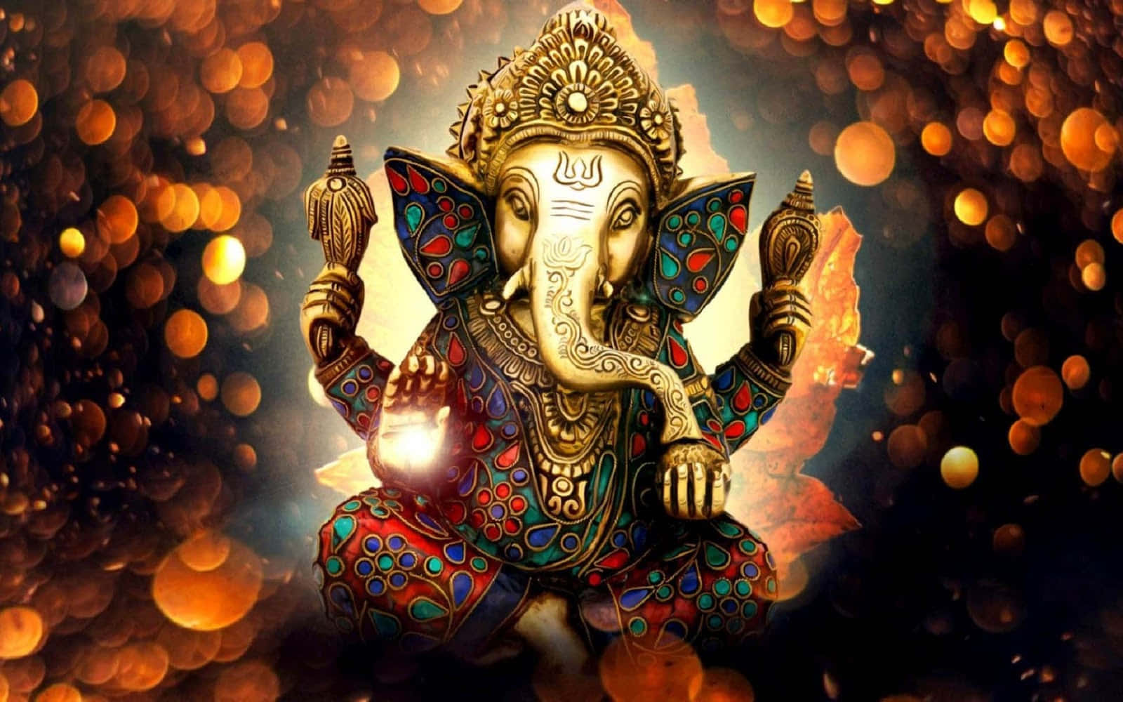Ganesh 桌布 壁紙 — 金色象神雕像飾以彩色圖案，在溫暖燈光的發光散景背景下寧靜地坐著。