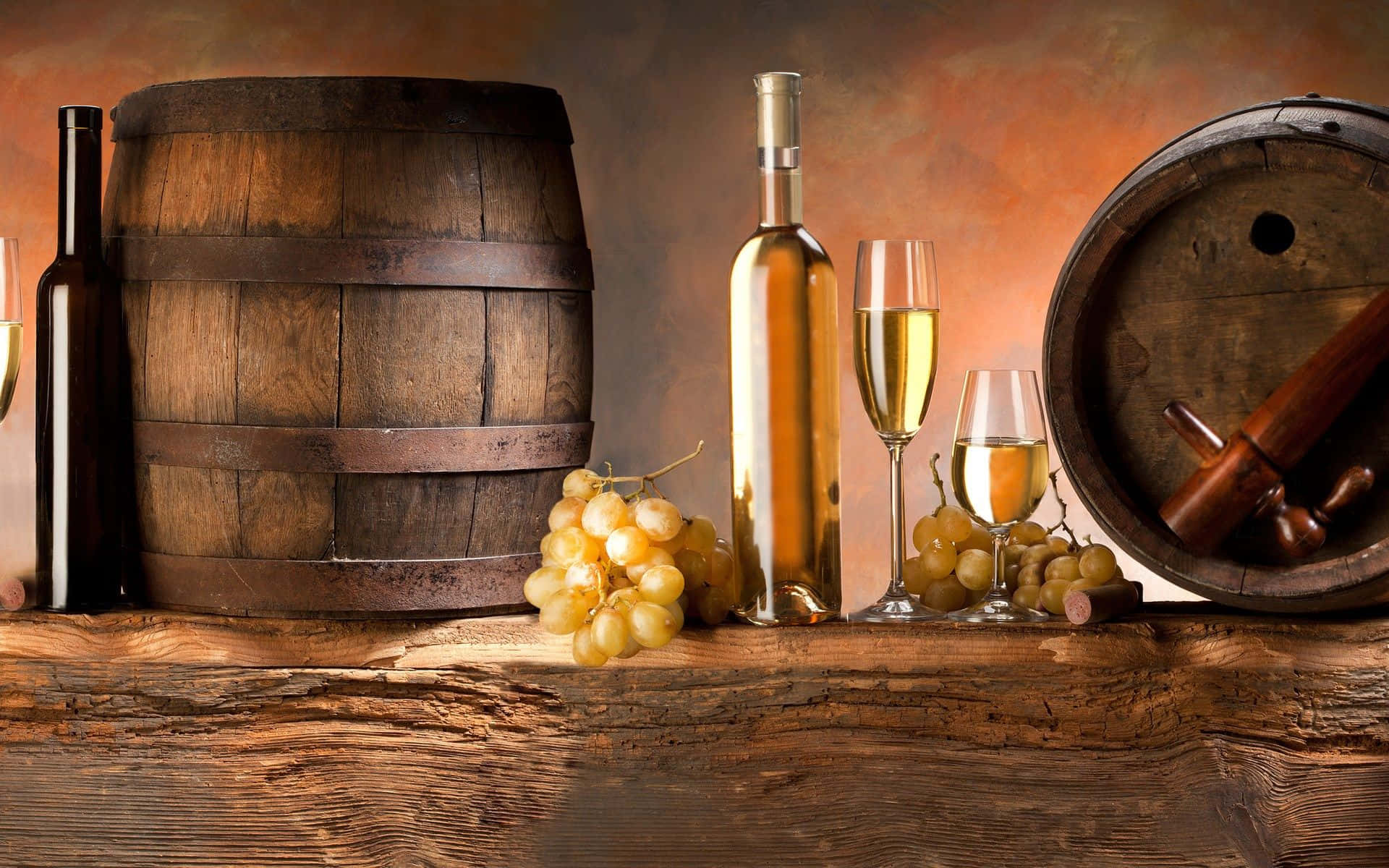 White Wine 桌布 壁紙 — 金色酒瓶、酒杯和新鮮葡萄放在質樸的木桌上，旁邊是陳年木桶，在溫暖的夕陽下。