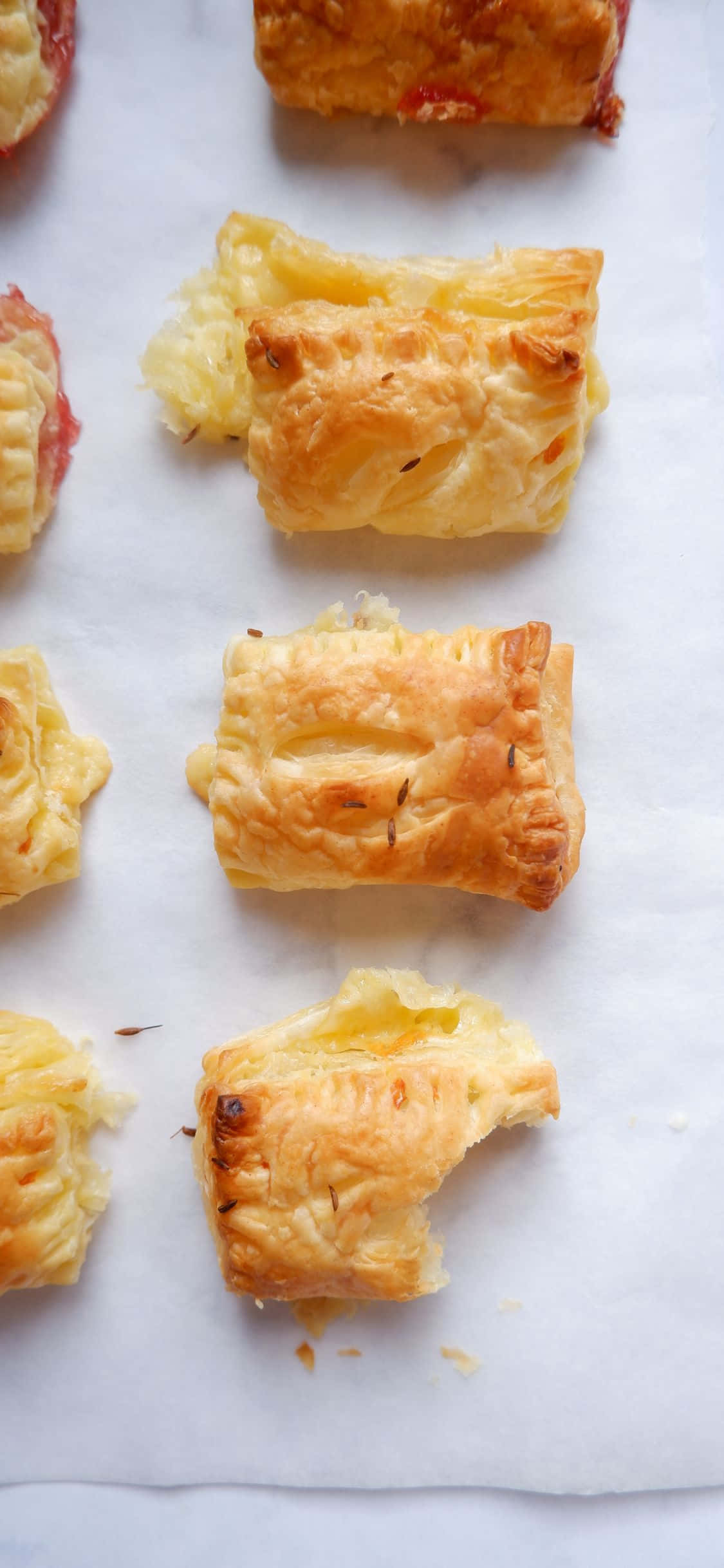 Pastry 桌布 壁紙 — 金色酥皮糕點，內餡紅色，放在白色烘焙紙上，有些破開露出奶油內餡。