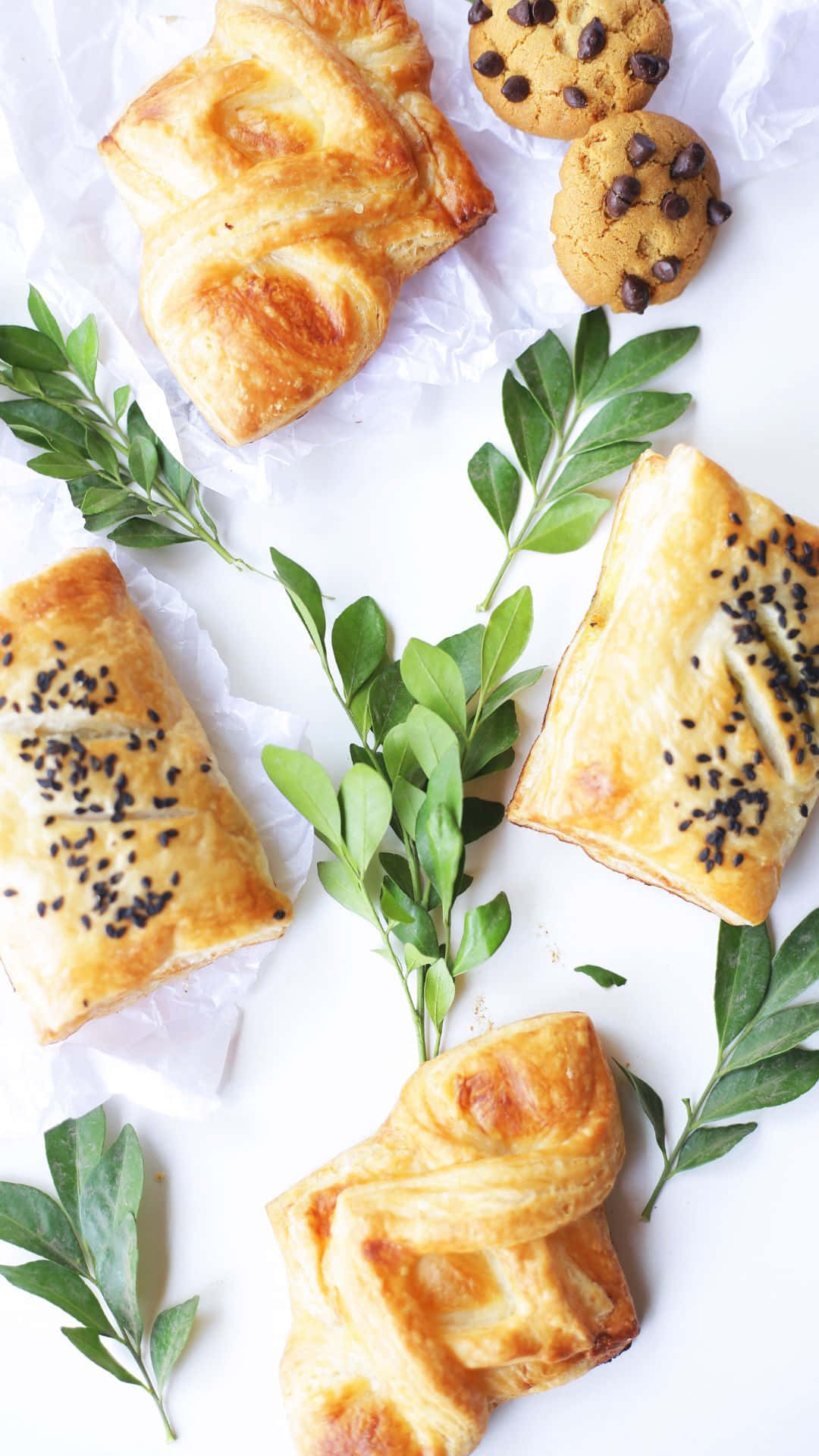 Pastry 桌布 壁紙 — 金色酥皮糕點和巧克力餅乾，搭配新鮮綠葉，放在白色烘焙紙上。