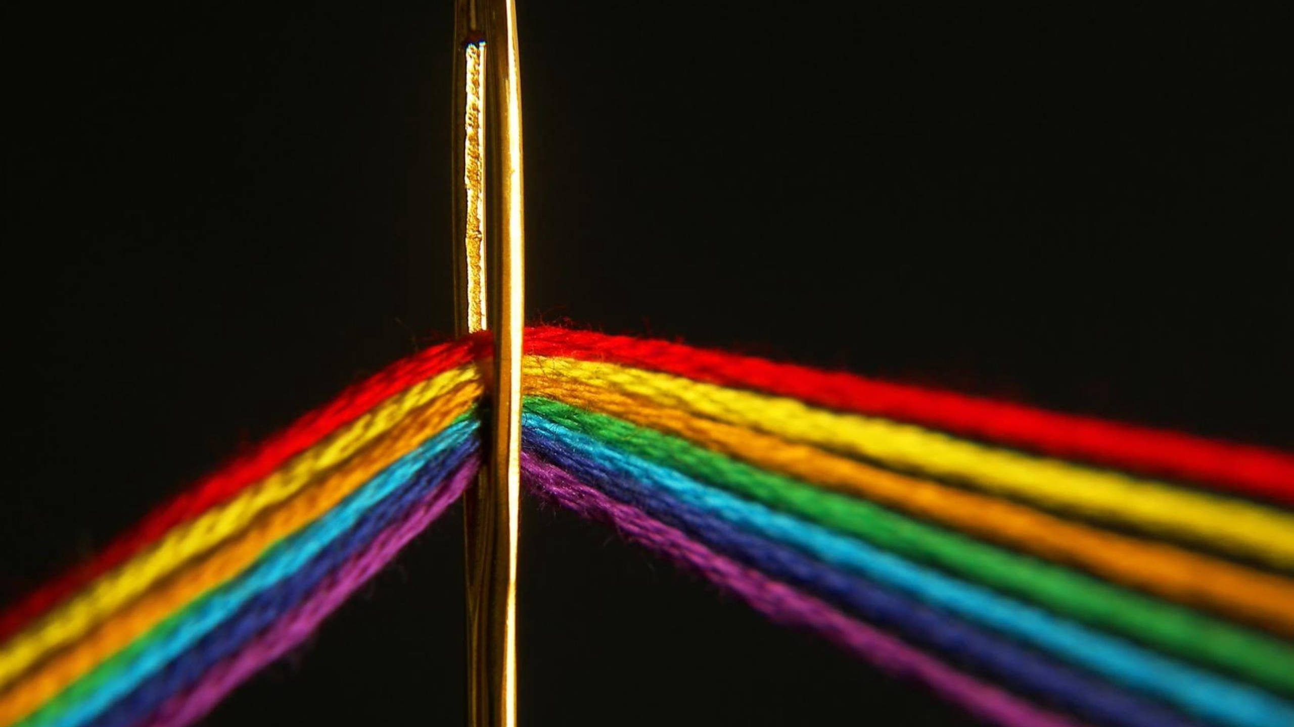 Spectrum 桌布 壁紙 — 金色針在純黑背景上分開鮮豔的彩虹色紗線。