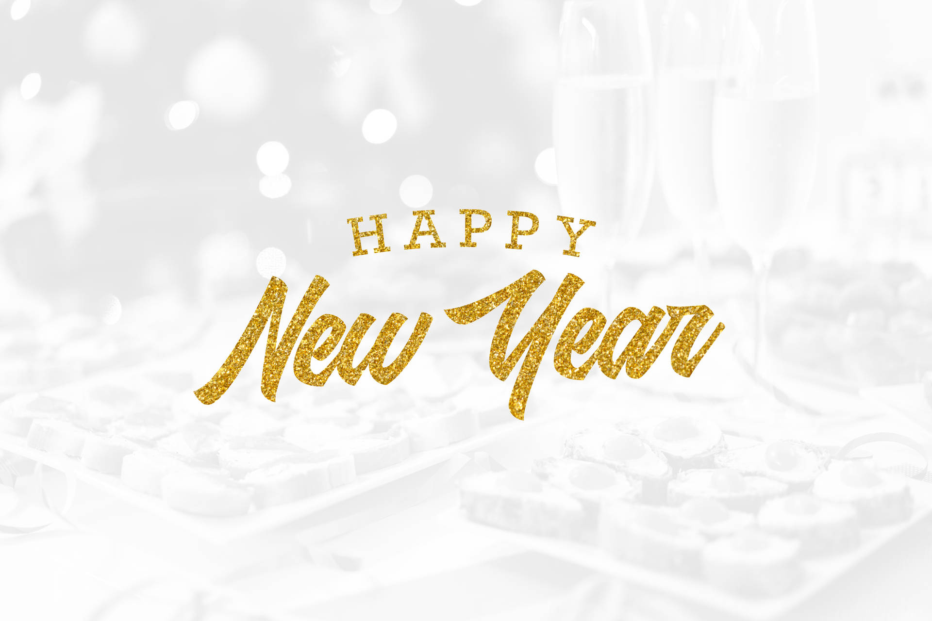 在模糊的香檳和巧克力上以金色亮粉呈現的Happy New Year文字。