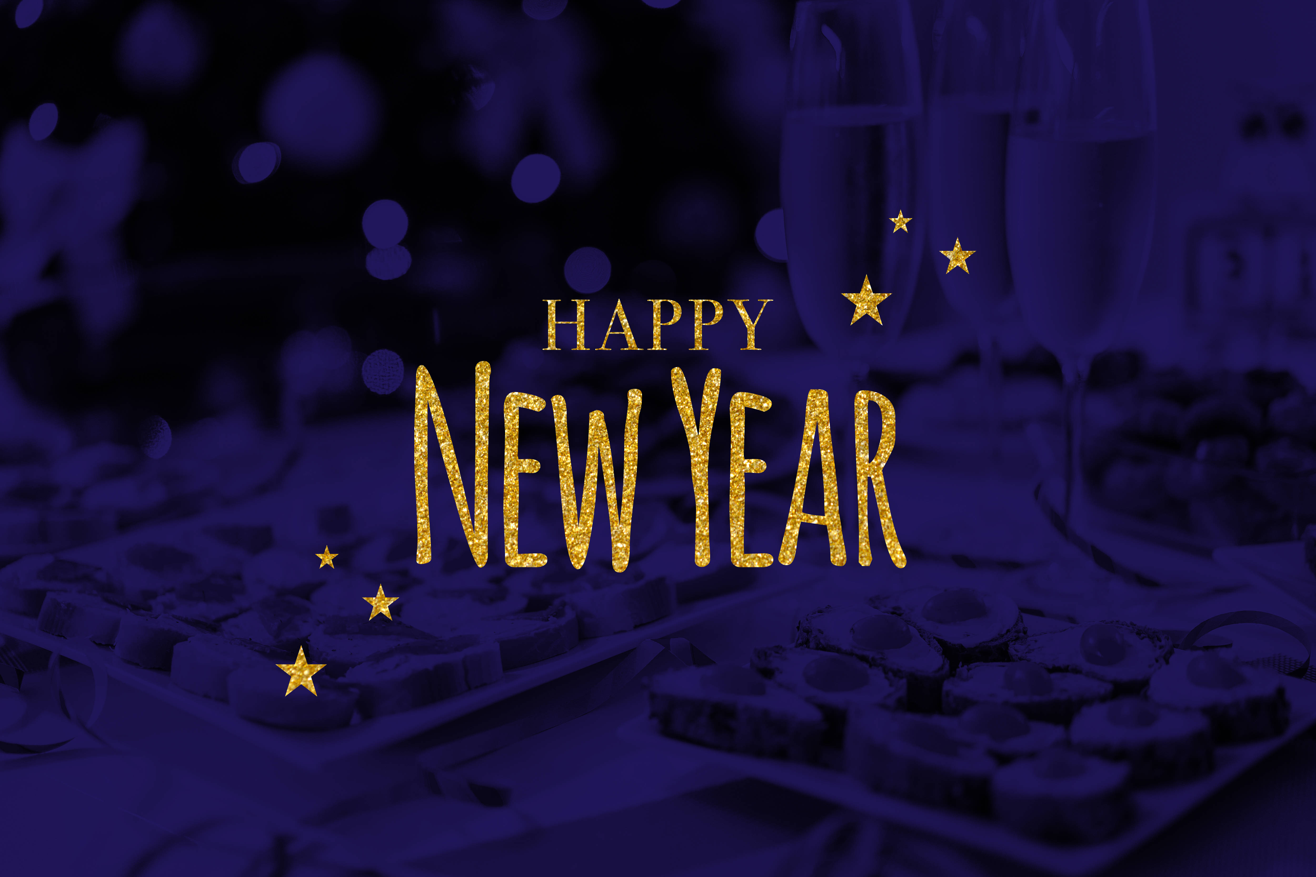 Stars 桌布 壁紙 — 金色閃爍的「Happy New Year」文字在模糊的紫色派對桌上閃耀，桌上放有香檳杯和巧克力。