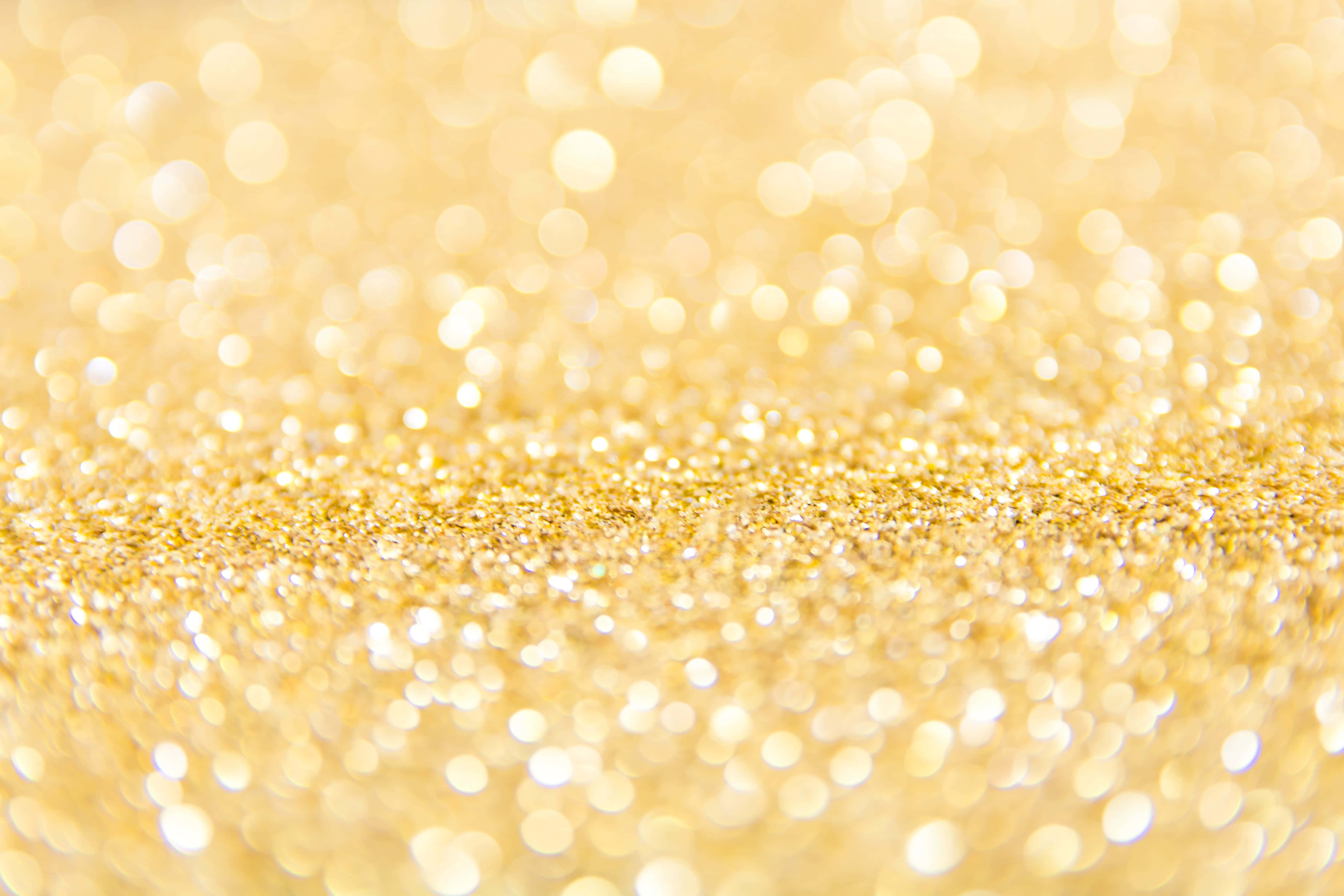 High Resolution Gold 桌布 壁紙 — 金色閃粉的特寫，搭配柔和散景燈光，營造出奢華且節慶的背景。