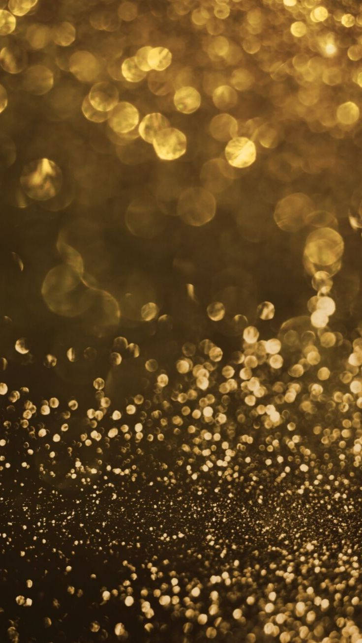 Bokeh 桌布 壁紙 — 金色閃粉粒子在深色背景上漂浮閃爍，營造出奢華的散景效果。