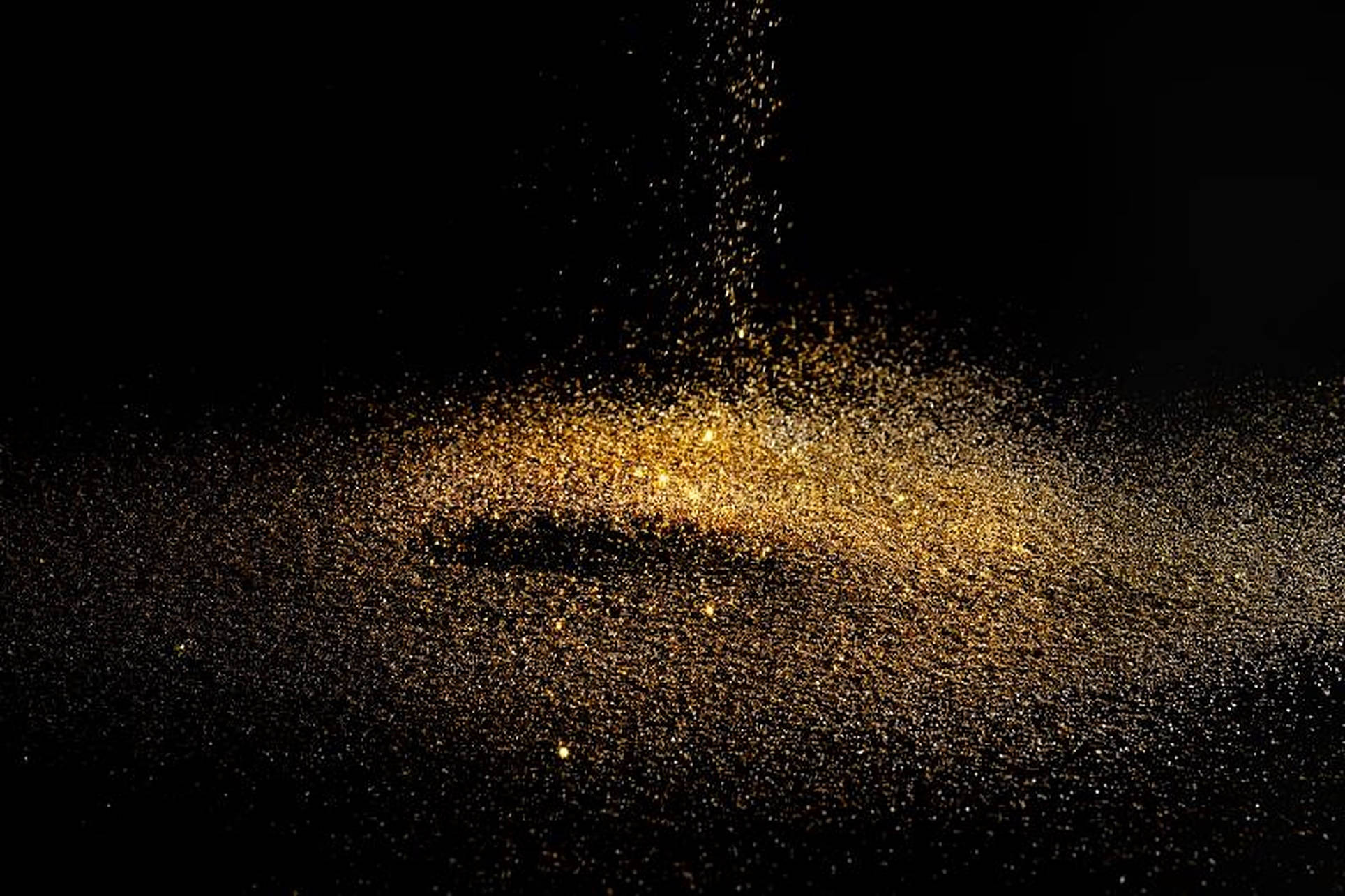 Dust 桌布 壁紙 — 金色閃粉粒子在純黑色背景上如瀑布般灑落並散開，營造出閃爍的動態效果。
