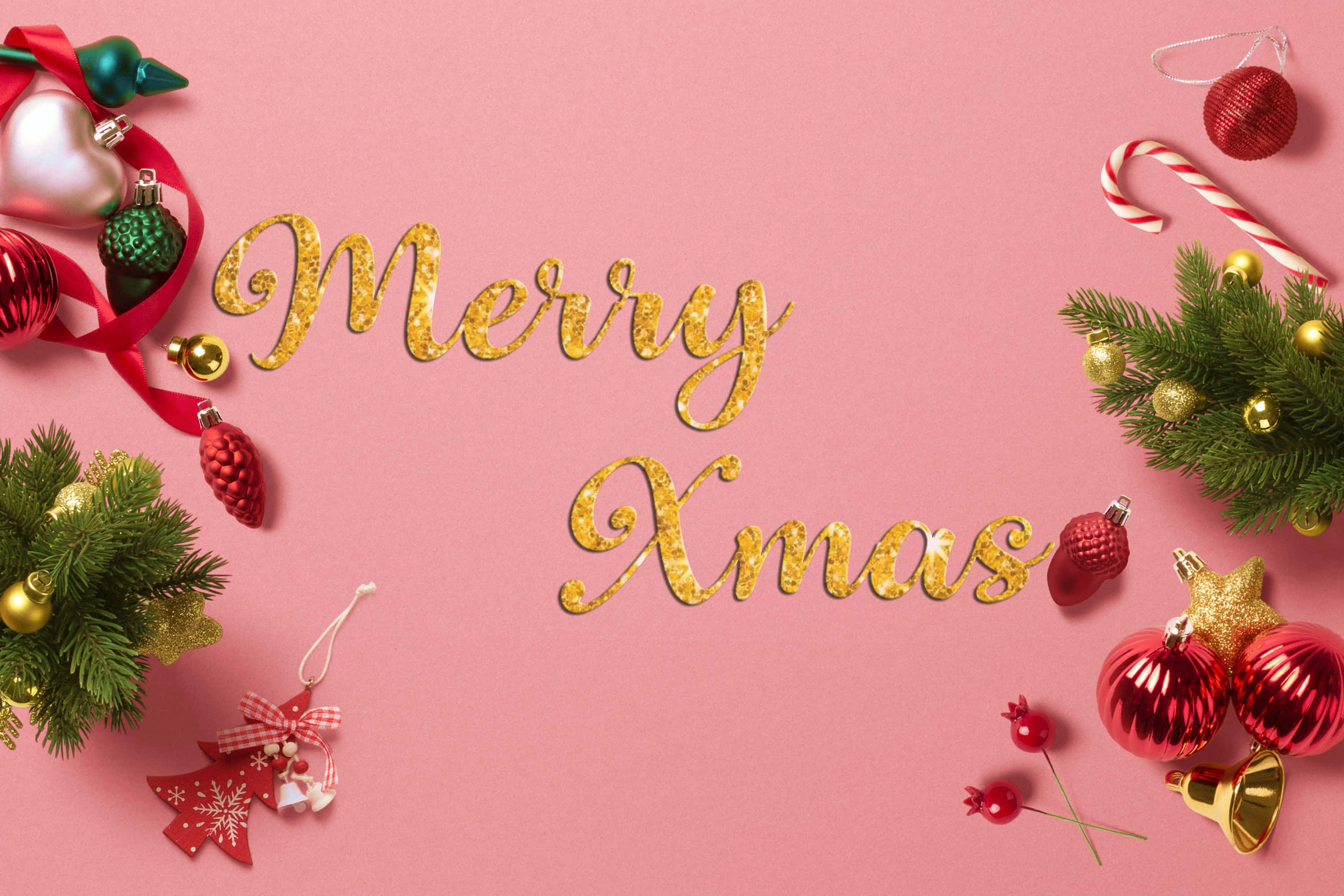 Festive 桌布 壁紙 — 金色閃閃發光的Merry Xmas文字居中在柔和的粉紅色背景上，周圍環繞著節日紅綠色裝飾品、松樹枝和拐杖糖。
