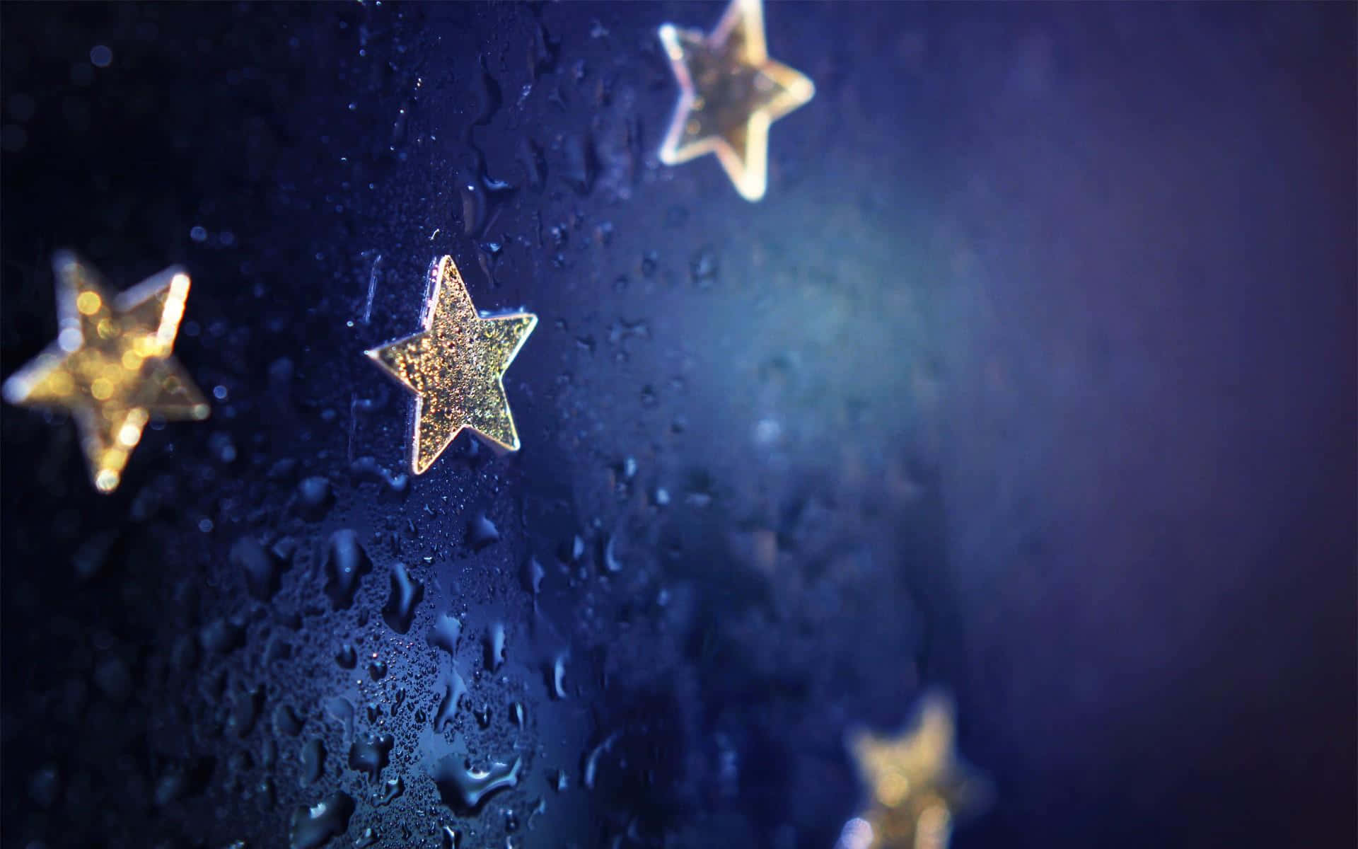 Cute Stars 桌布 壁紙 — 金色閃閃發光的星星緊貼在雨點斑駁的窗戶上，背景是深藍色的夜空。