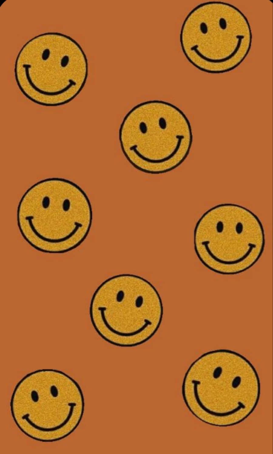 Smiley 桌布 壁紙 — 金色閃閃發光的笑臉在溫暖的陶土背景上以分散的圖案漂浮。
