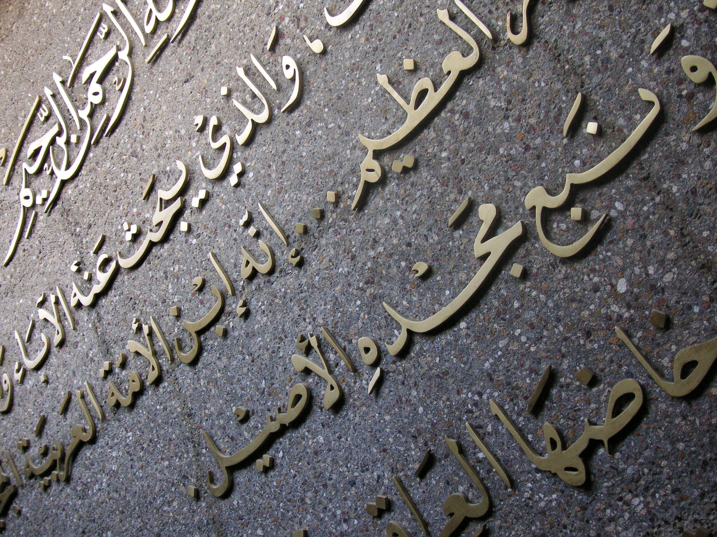 Iraq 桌布 壁紙 — 金色阿拉伯書法優雅地蝕刻在紋理灰色石面上，搭配柔和環境光。