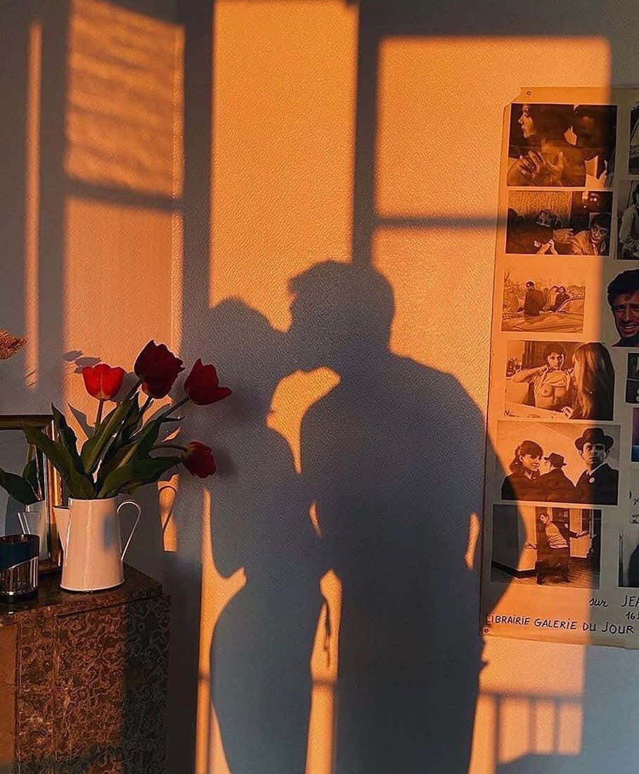 Cute Boyfriend 桌布 壁紙 — 金色陽光在紅鬱金香和復古照片旁的牆上投射出一對擁抱情侶的溫柔影子。
