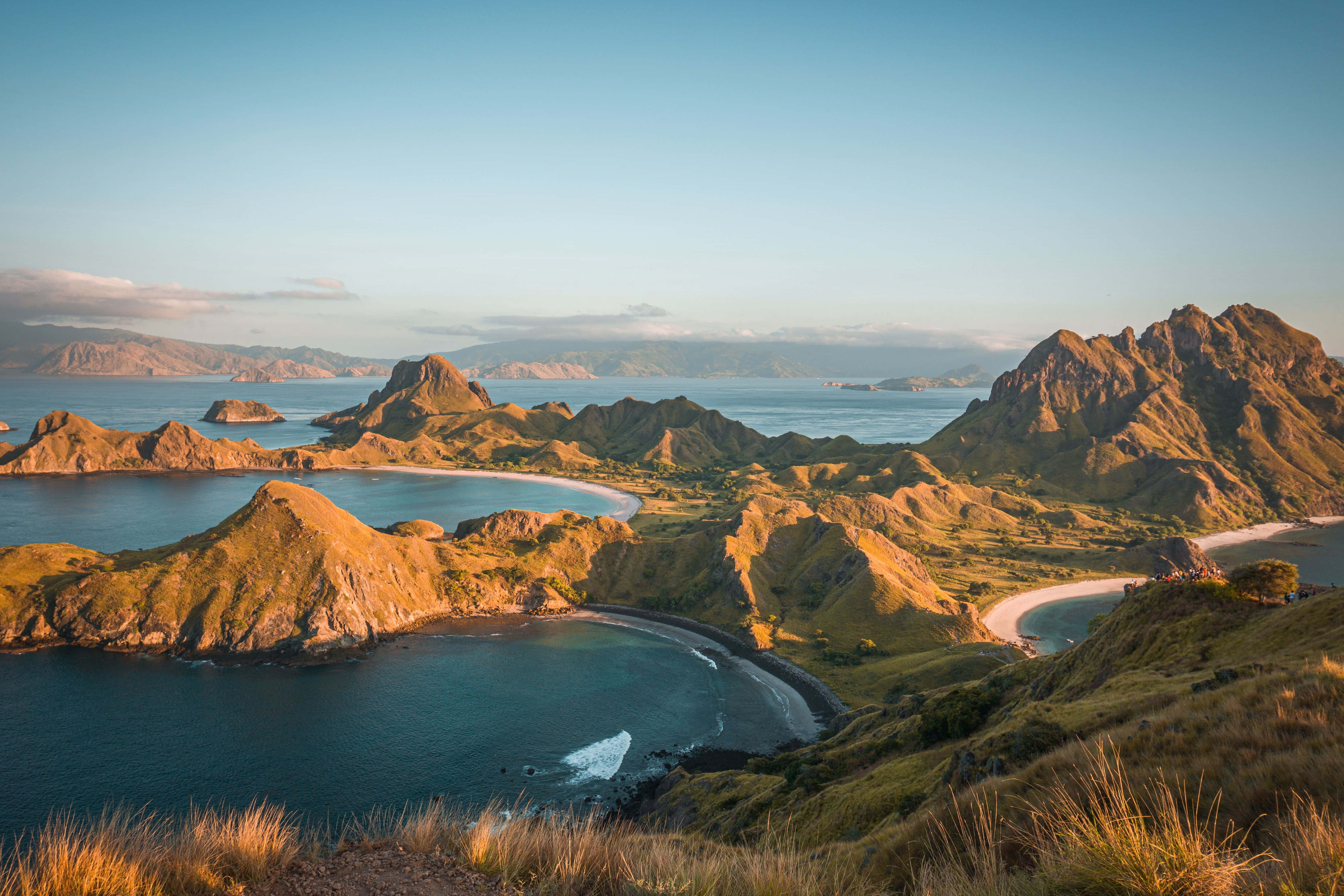 島嶼 桌布 壁紙 — 金色陽光灑落在崎嶇的火山島和碧綠的海灣上，形成寧靜的海岸天堂。