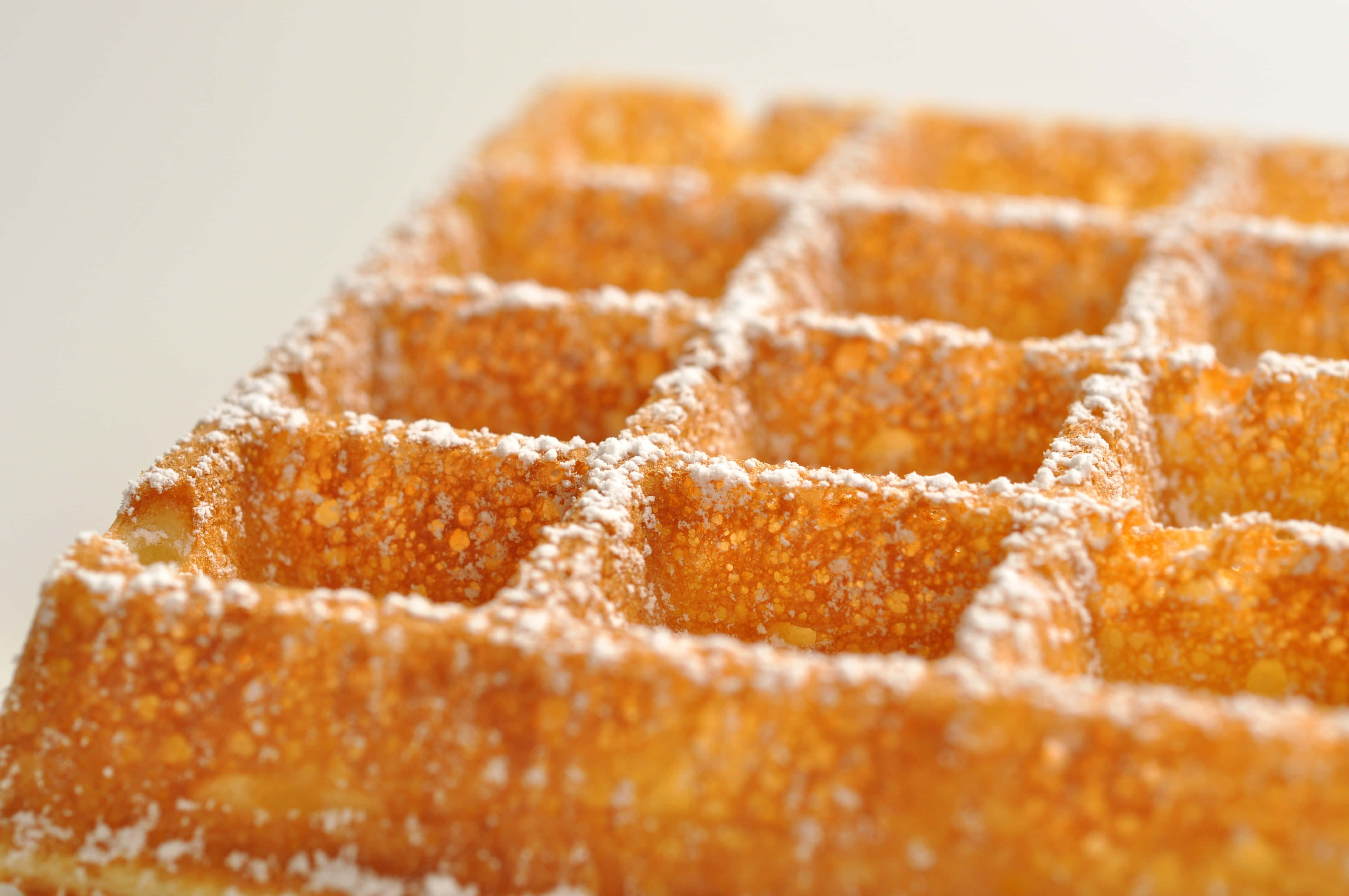 Waffle 桌布 壁紙 — 金色鬆餅撒上糖粉，柔焦效果，背景簡潔。