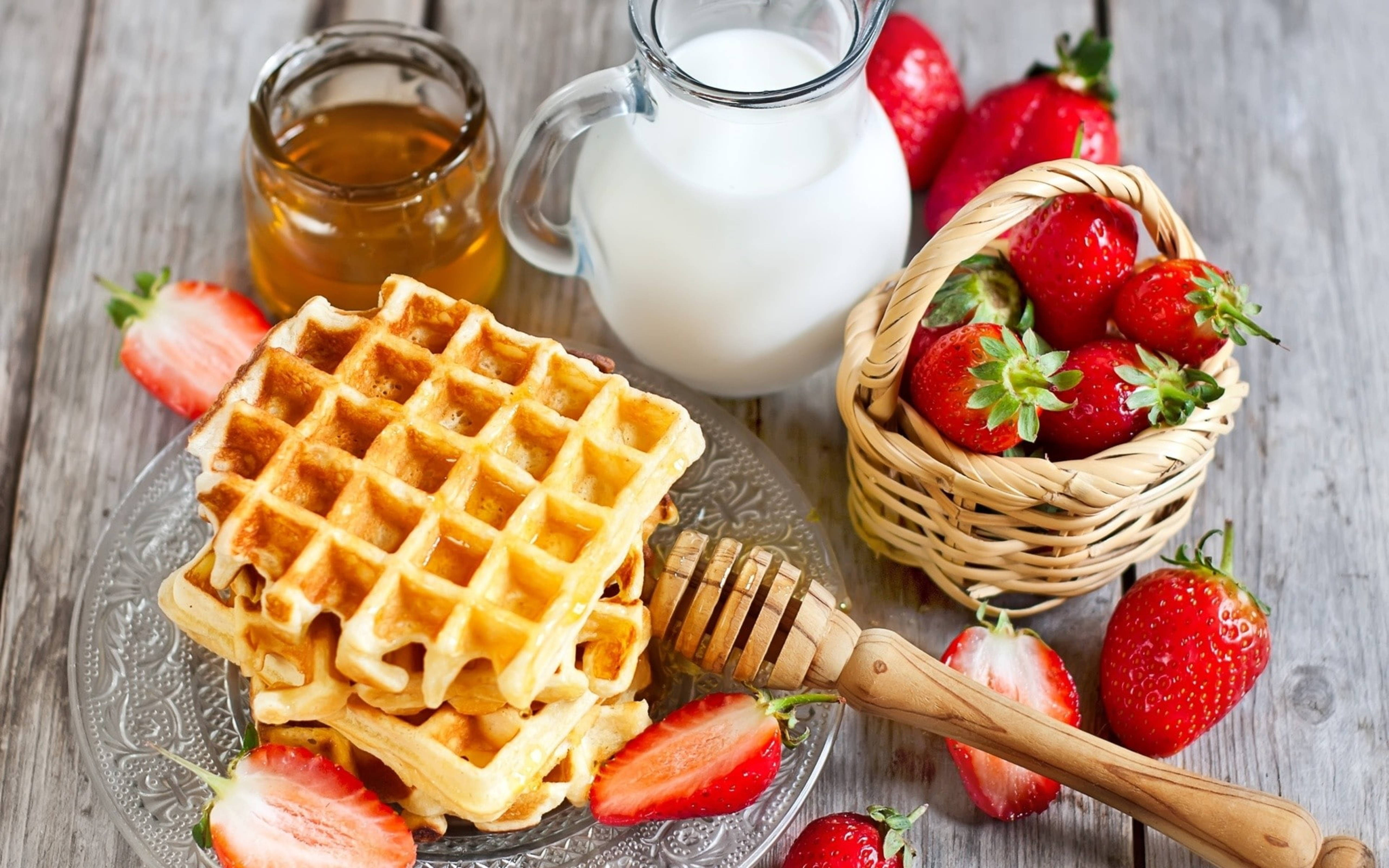 Waffle 桌布 壁紙 — 金色鬆餅疊放在玻璃盤上，旁邊放著一籃新鮮草莓、蜂蜜和牛奶，置於鄉村風木桌上。