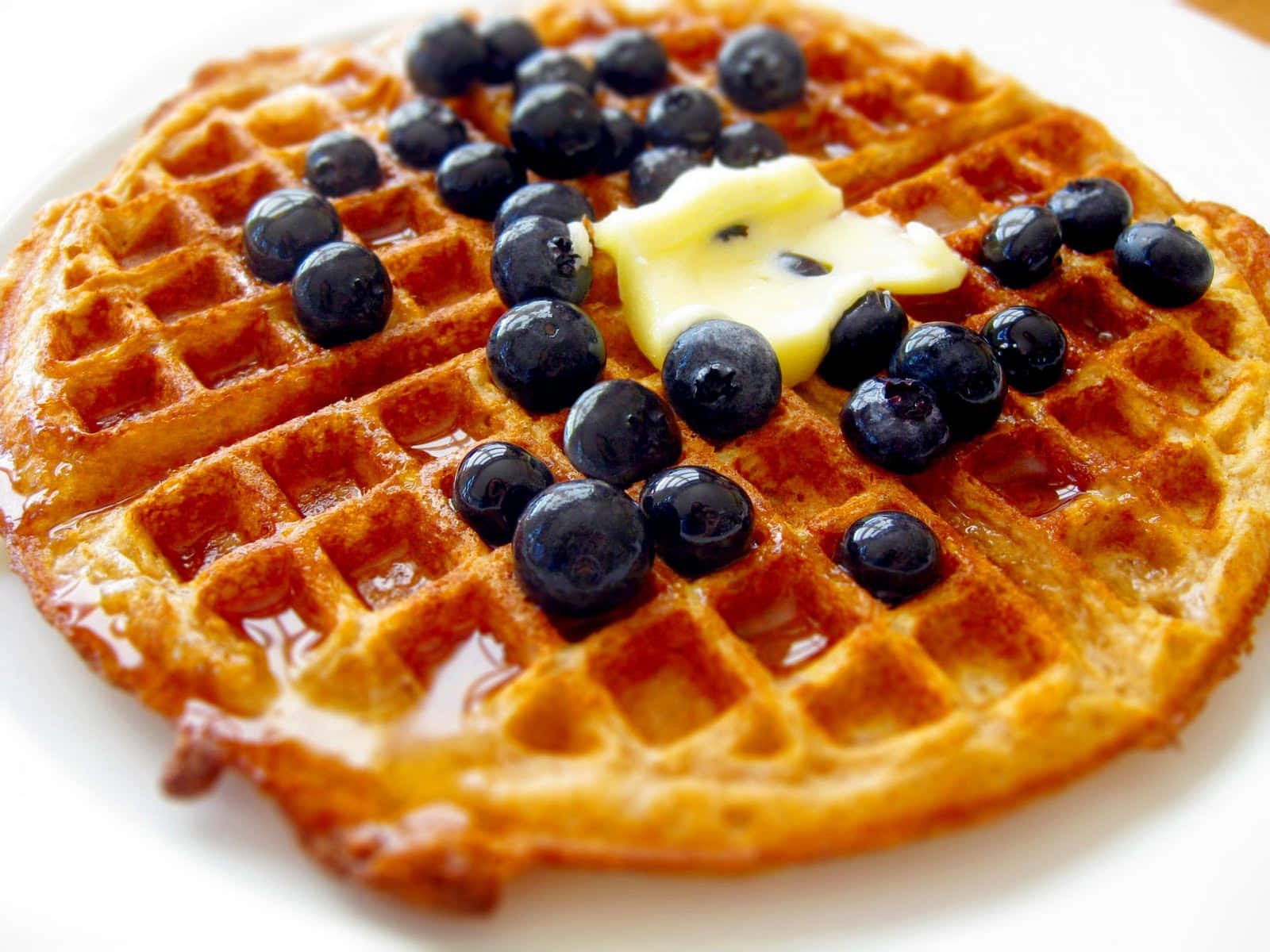 Waffle 桌布 壁紙 — 金色鬆餅配上閃亮糖漿、藍莓和融化奶油，放在白色盤子上。