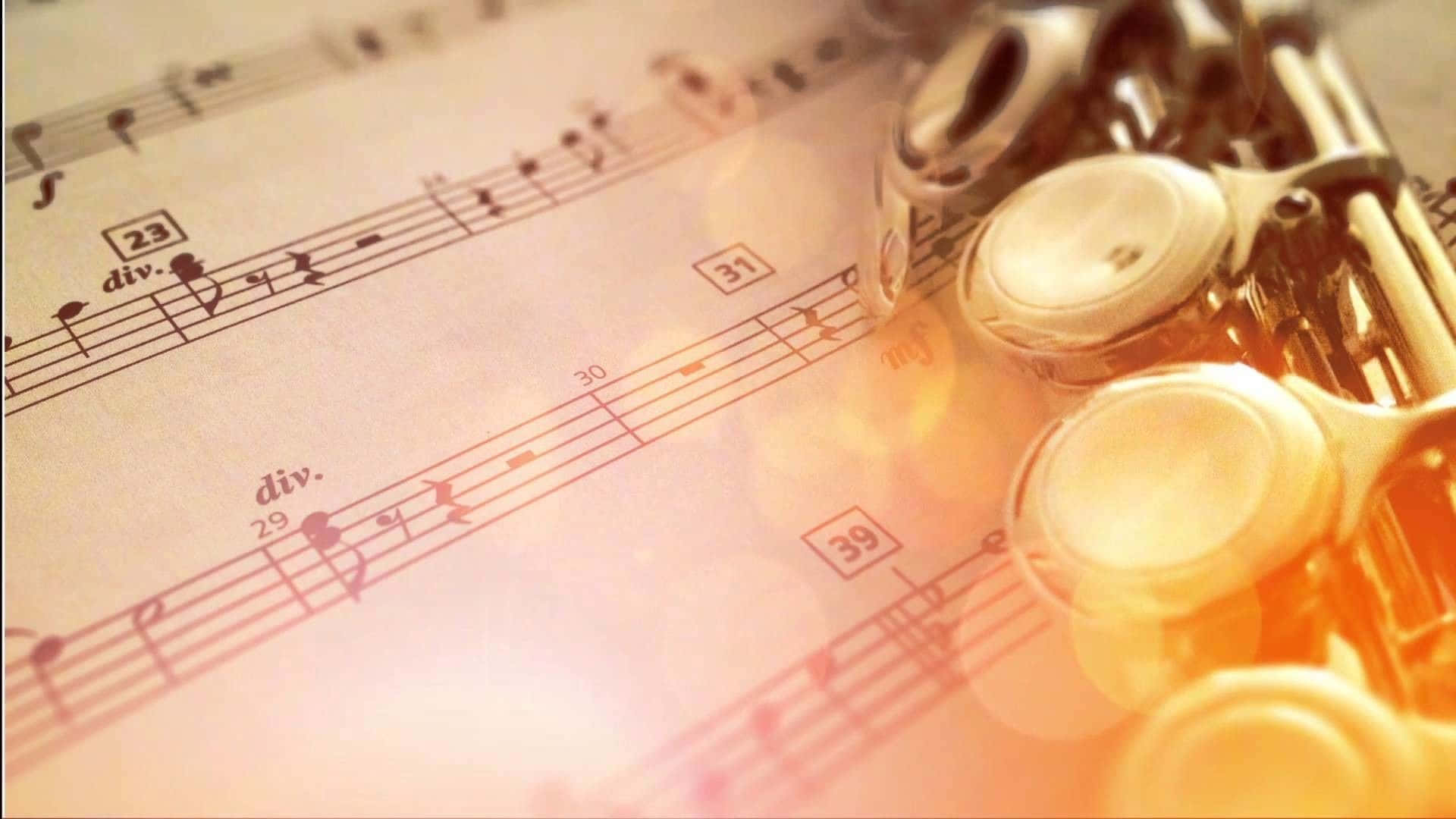 Classical Music 桌布 壁紙 — 金色黃銅長笛溫暖地放在浸浴在柔和琥珀色燈光下的復古樂譜上。