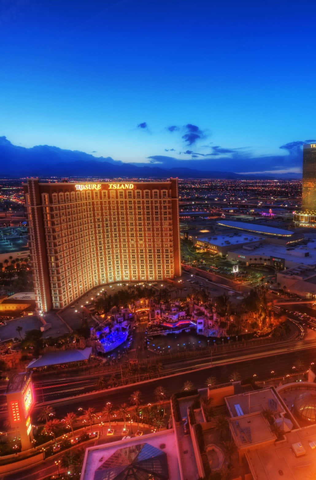Las Vegas Phone 桌布 壁紙 — 金銀島酒店在暮色天空下溫暖發光的鳥瞰圖，城市燈光在下方蔓延。