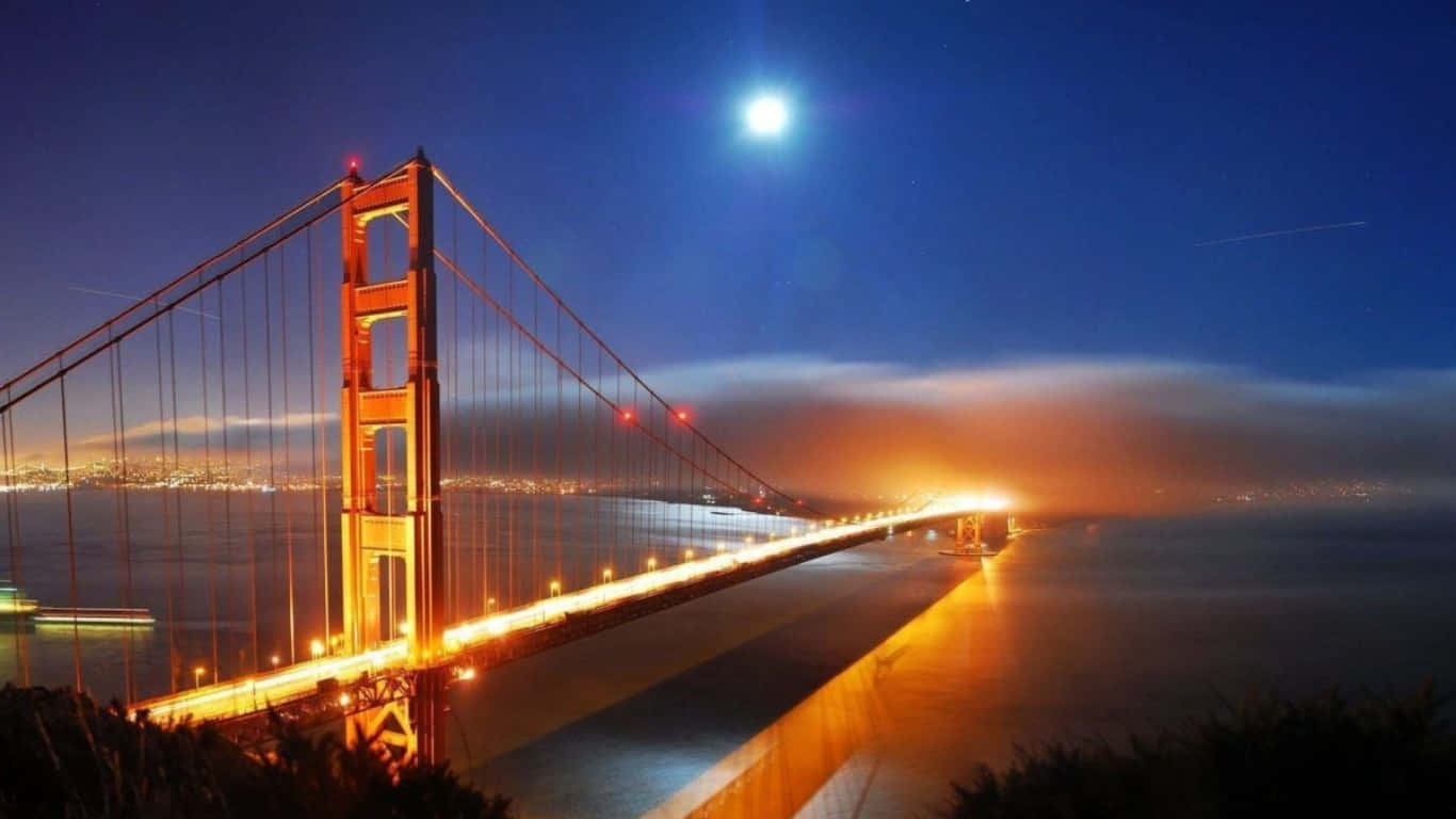 1366x768 San Francisco 桌布 壁紙 — 金門大橋在明亮的月光下溫暖地發光，城市燈光在海灣對岸閃爍。