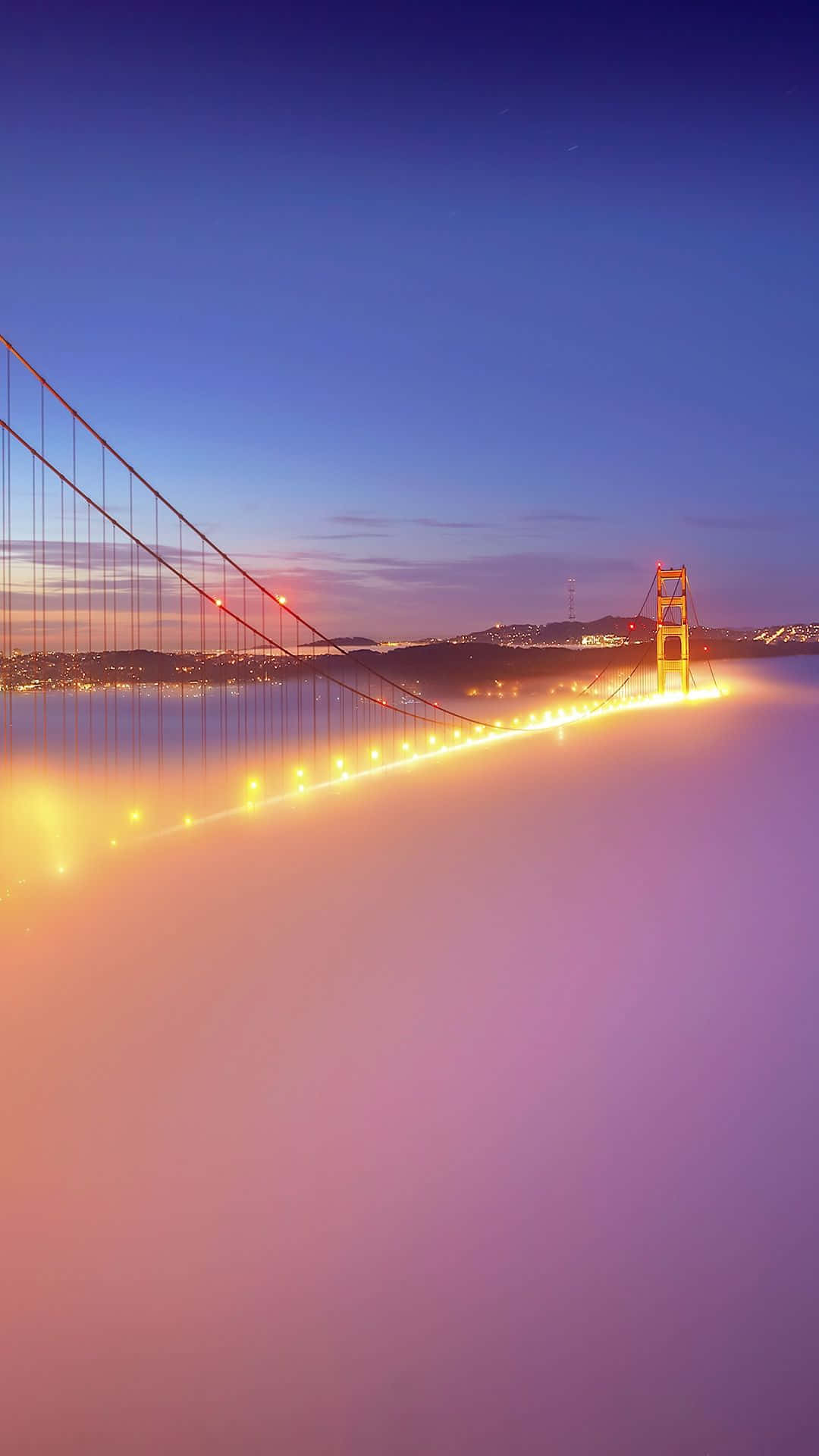 Android San Francisco 桌布 壁紙 — 金門大橋在暮色中透過濃厚的紫色和橙色霧氣溫暖地發光，下方城市燈光閃爍。