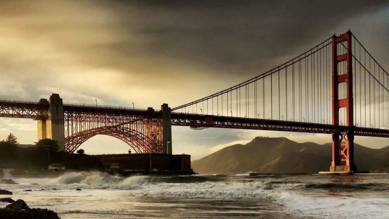 1366x768 San Francisco 桌布 壁紙 — 金門大橋在暴風雨的天空下巍然聳立，海浪在其標誌性的紅色橋塔下翻騰。