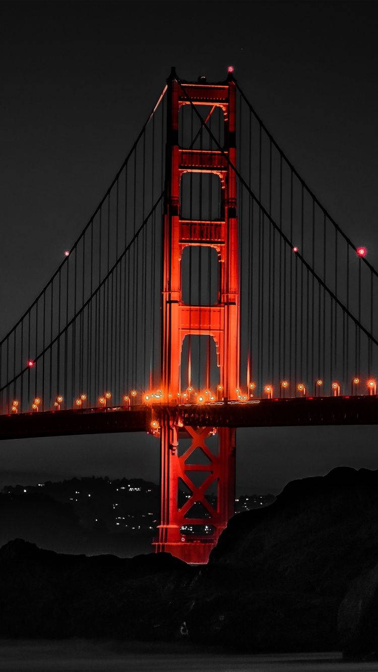 san francisco iPhone 桌布 壁紙 — 金門大橋在漆黑的夜空中發出火紅的光芒，下方城市燈光閃爍。