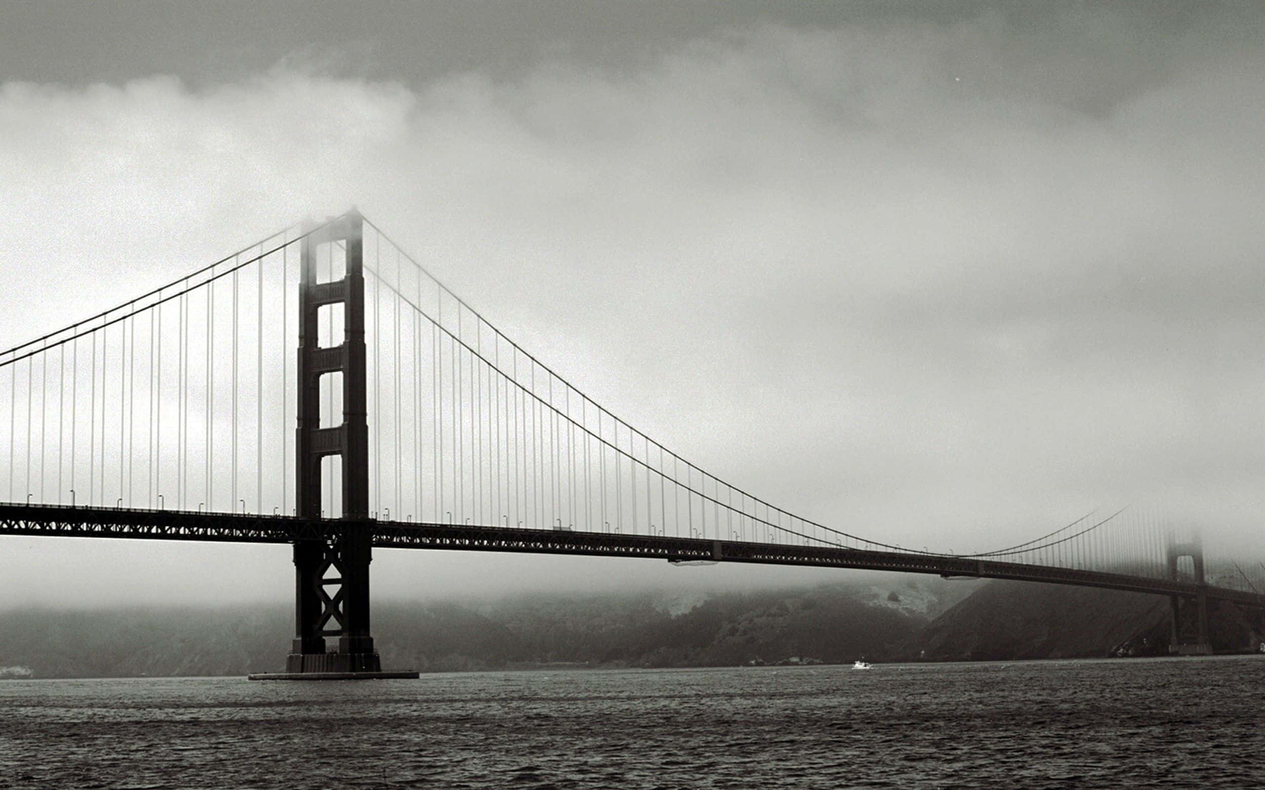 San Francisco Black And White 桌布 壁紙 — 金門大橋在陰天天空下部分被霧籠罩在水面上的黑白景觀。