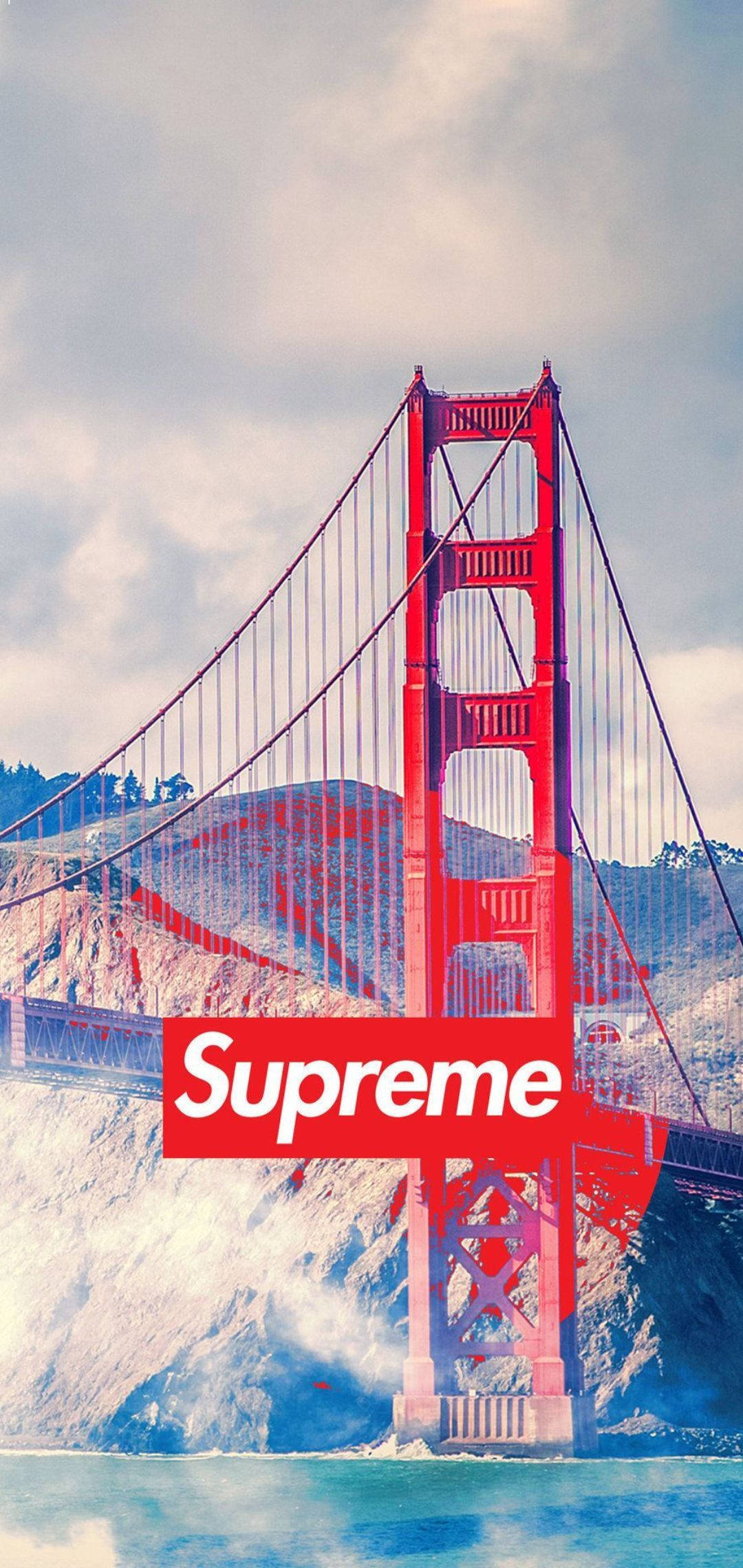 Cool Supreme 桌布 壁紙 — 金門大橋在陰雲密布的天空下以紅色大膽聳立，上面覆蓋著一個巨大的Supreme標誌。