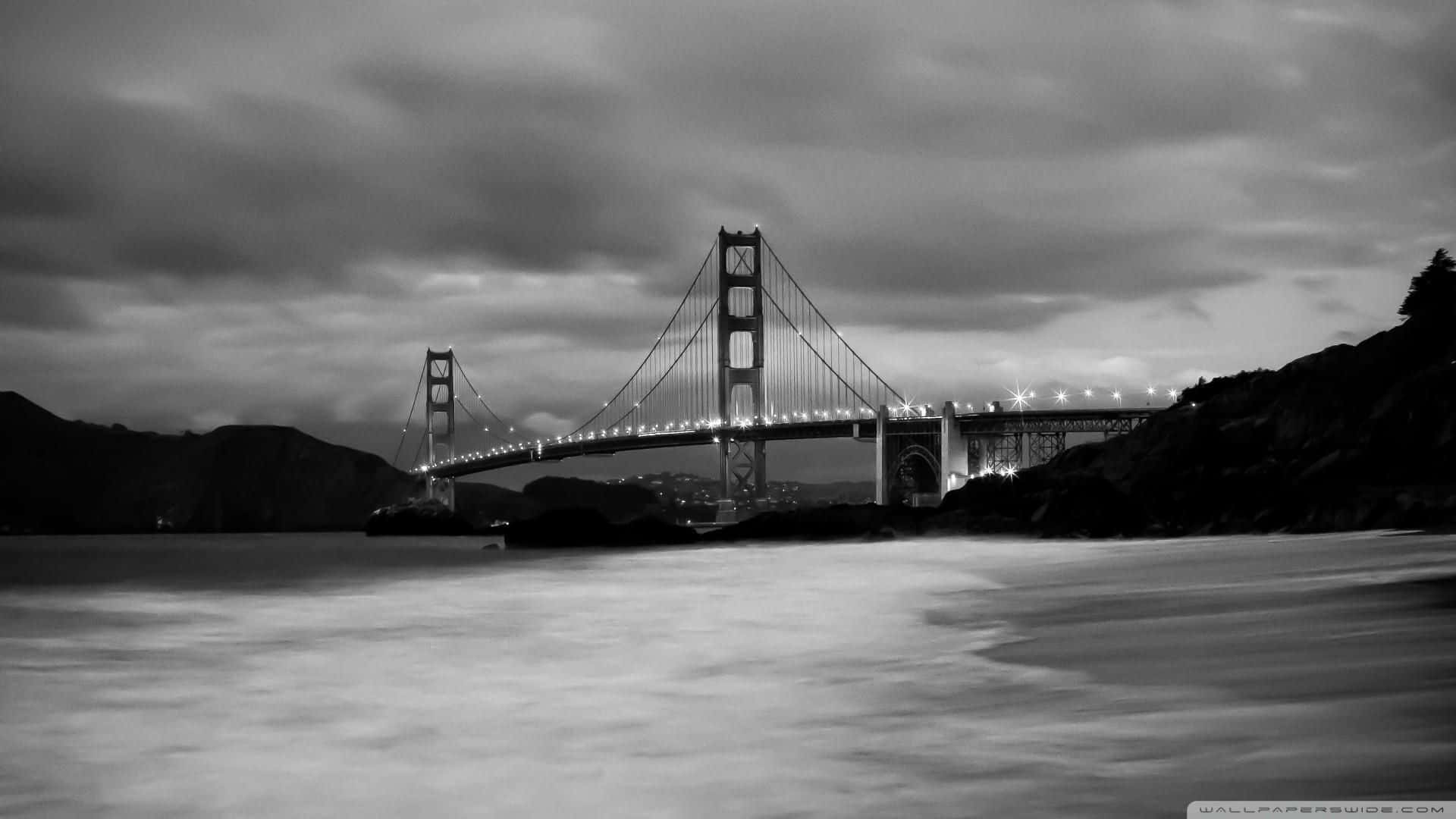 San Francisco Black And White 桌布 壁紙 — 金門大橋在黃昏時的單色長曝光，水面模糊，天空多雲。