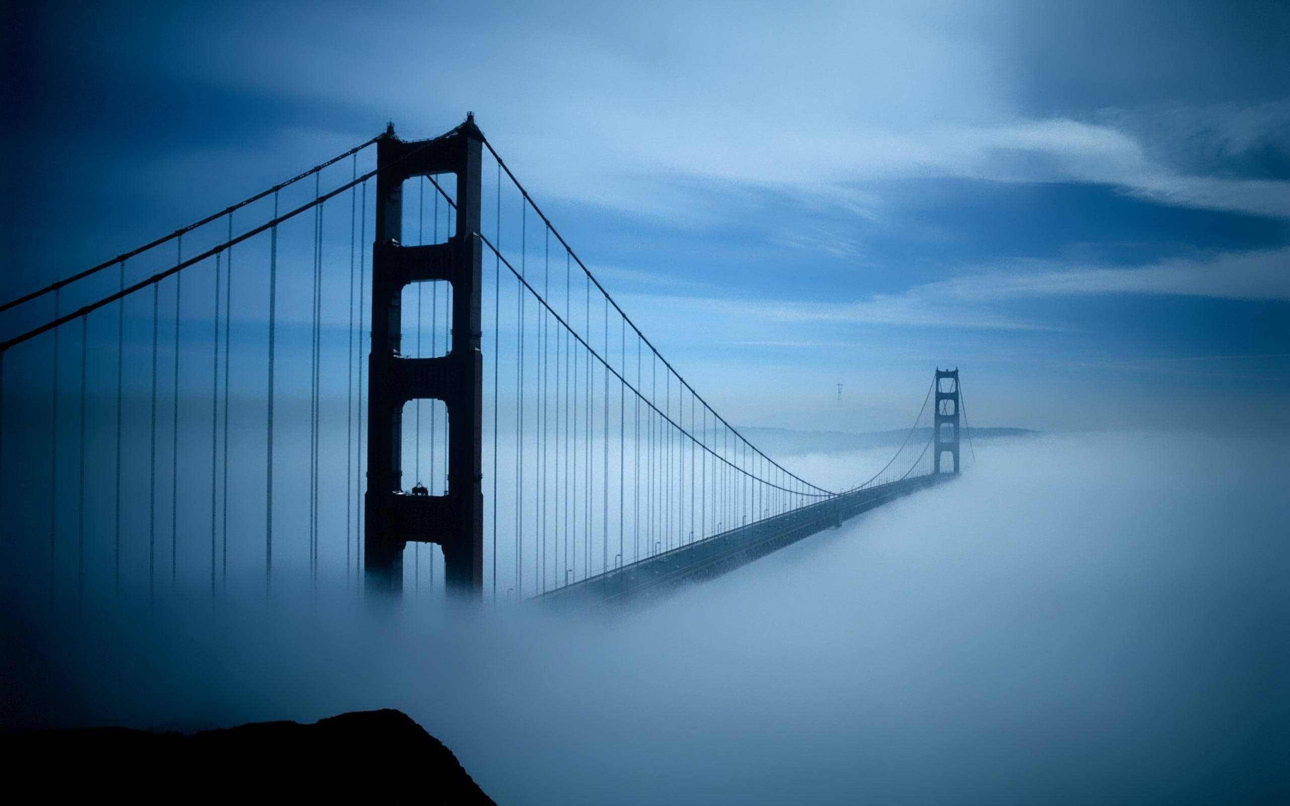 San Francisco Phone 桌布 壁紙 — 金門大橋從濃密的藍色迷霧中浮現，背景是帶有縷縷雲彩的憂鬱暮色天空。