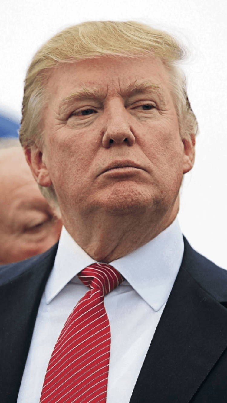 donald trump 桌布 壁紙 — 金髮男子身穿深色西裝和紅色條紋領帶，在明亮背景下的特寫肖像。