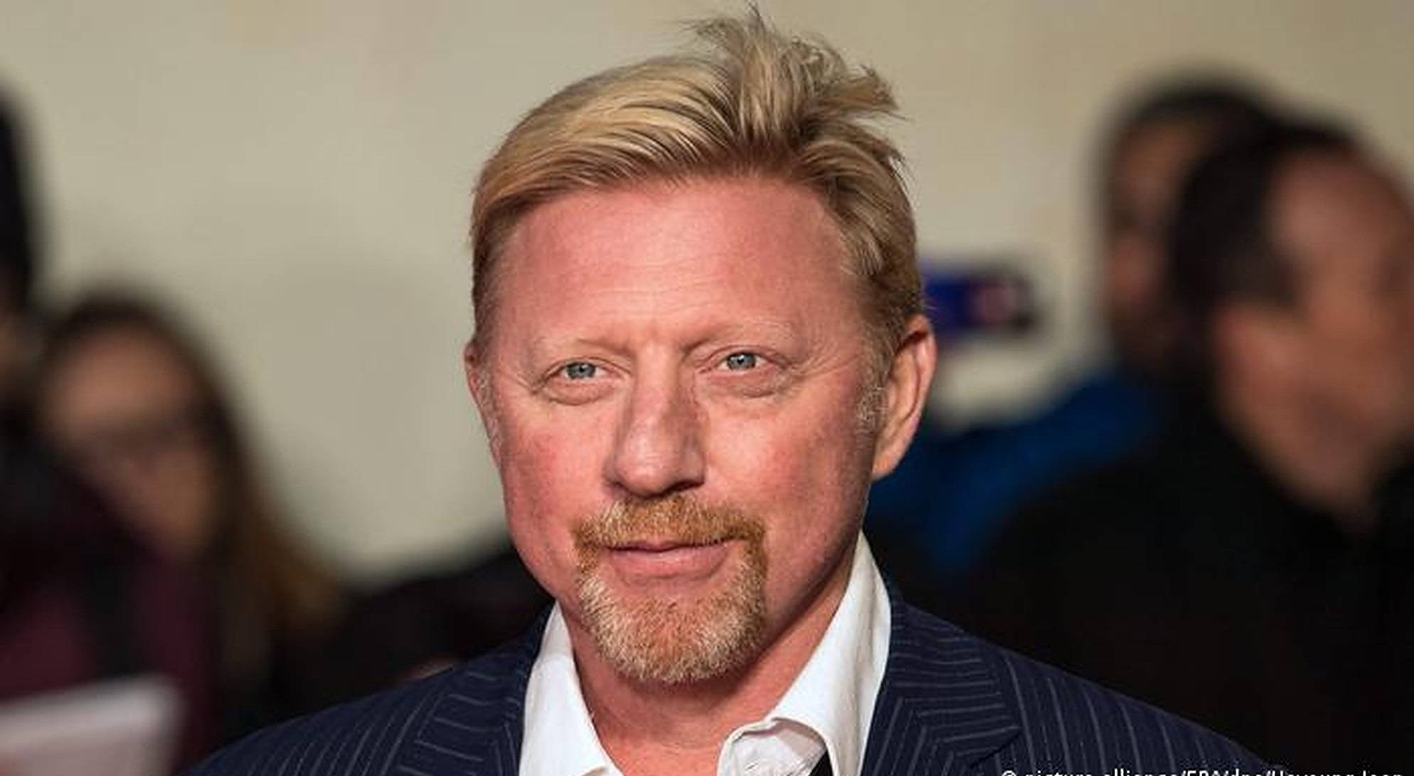 Boris Becker 桌布 壁紙 — 金髮留山羊鬍鬚的男人，穿著細條紋西裝，在模糊背景前的特寫肖像。