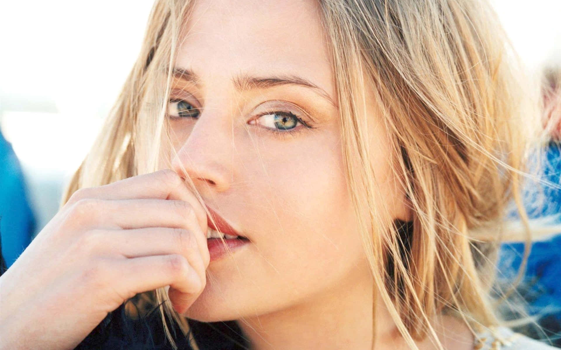 Estella Warren 桌布 壁紙 — 金髮碧眼女子的特寫肖像，在明亮背景下用手輕觸嘴唇。