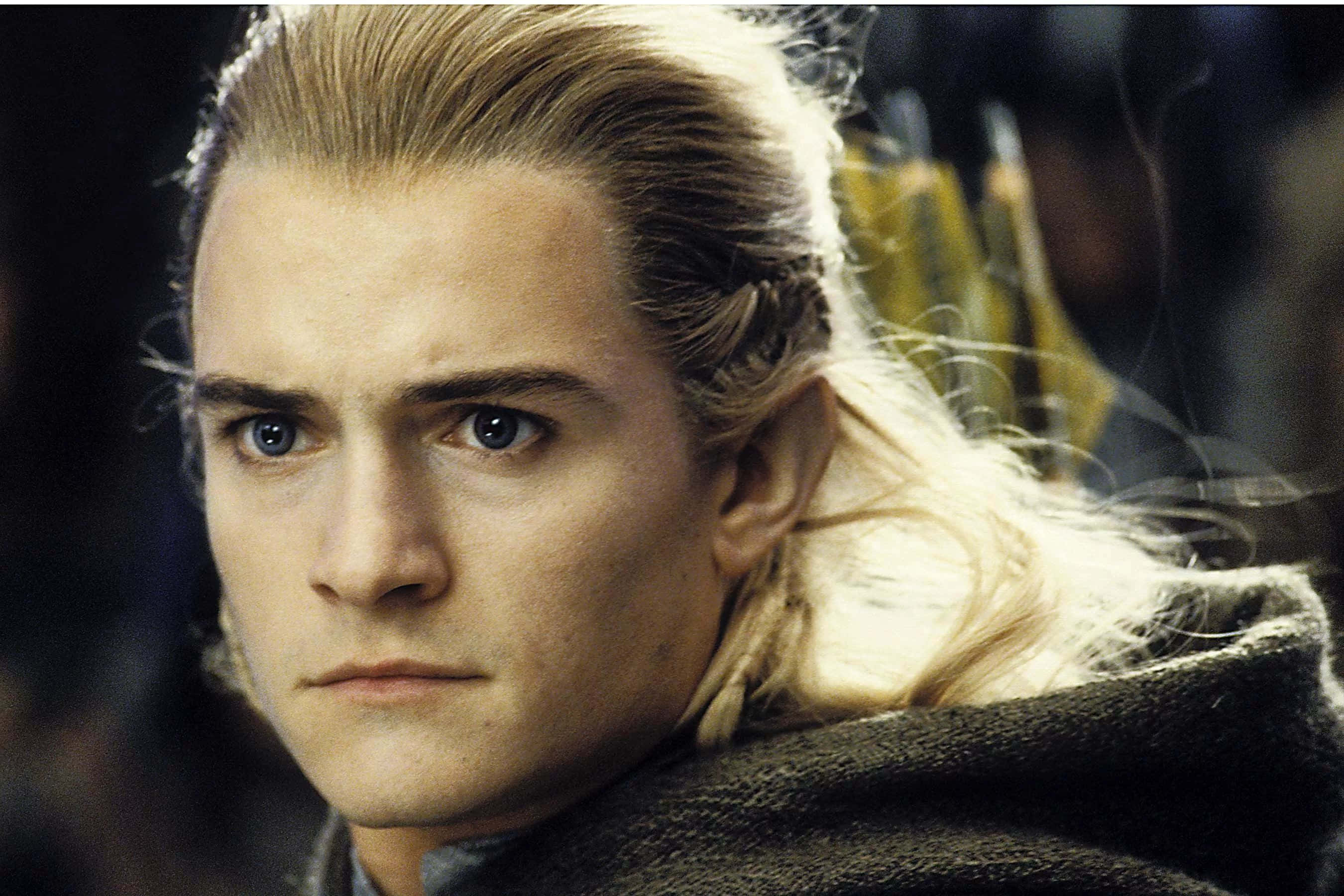 legolas 桌布 壁紙 — 金髮精靈的關閉肖像，擁有強烈的藍眼睛和辮子頭髮，穿著深色斗篷。